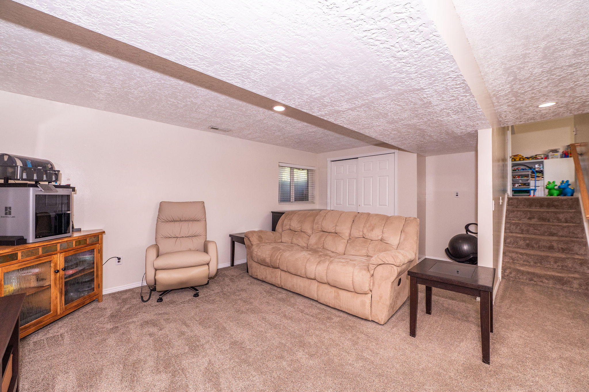 Carpeted recreation room featuring recessed lighting, a window, and a built-in closet with bi-fold doors