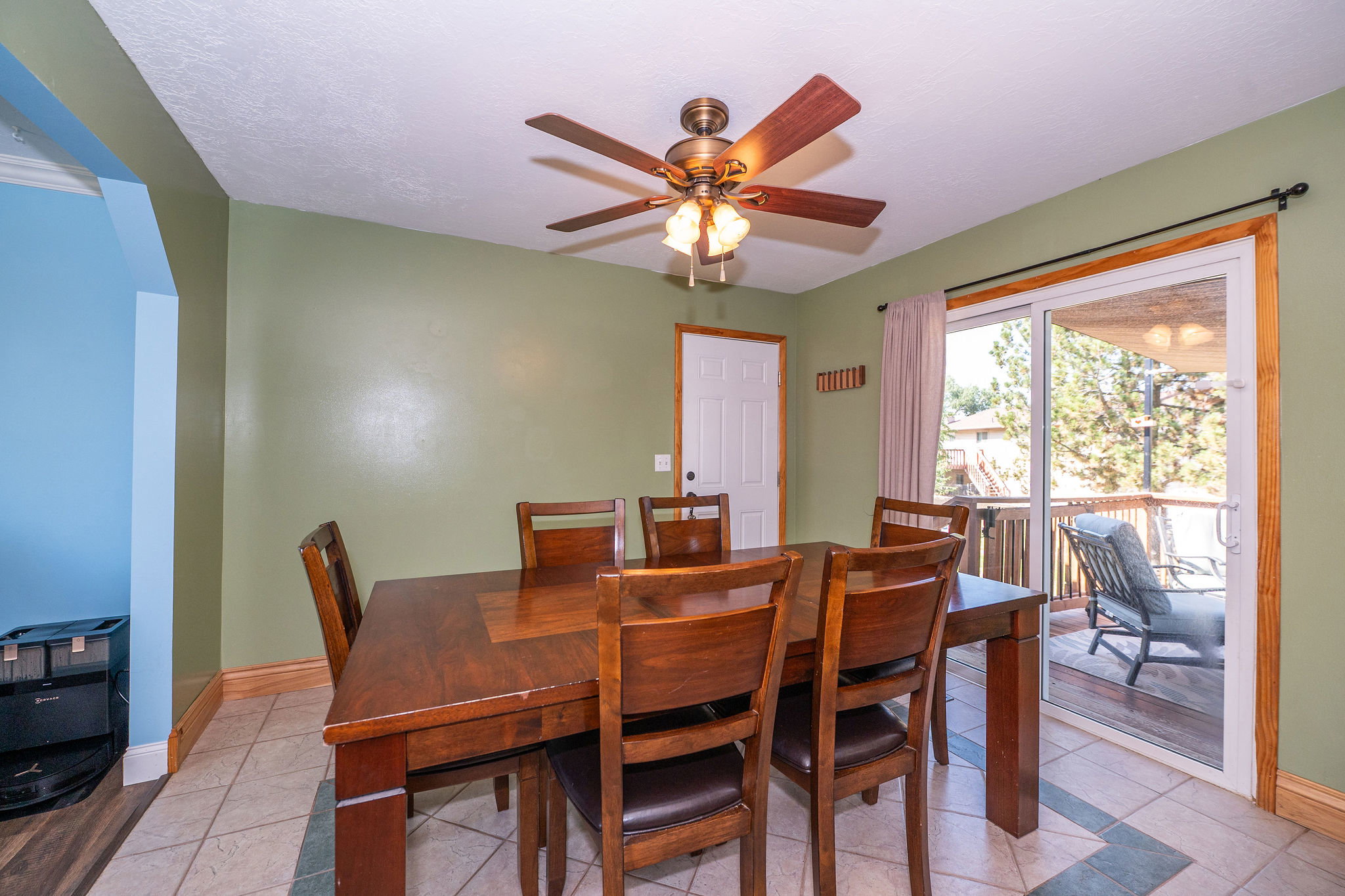 Dining area featuring tiled flooring, a ceiling fan with integrated lighting, and direct access to an outdoor deck via a sliding glass door