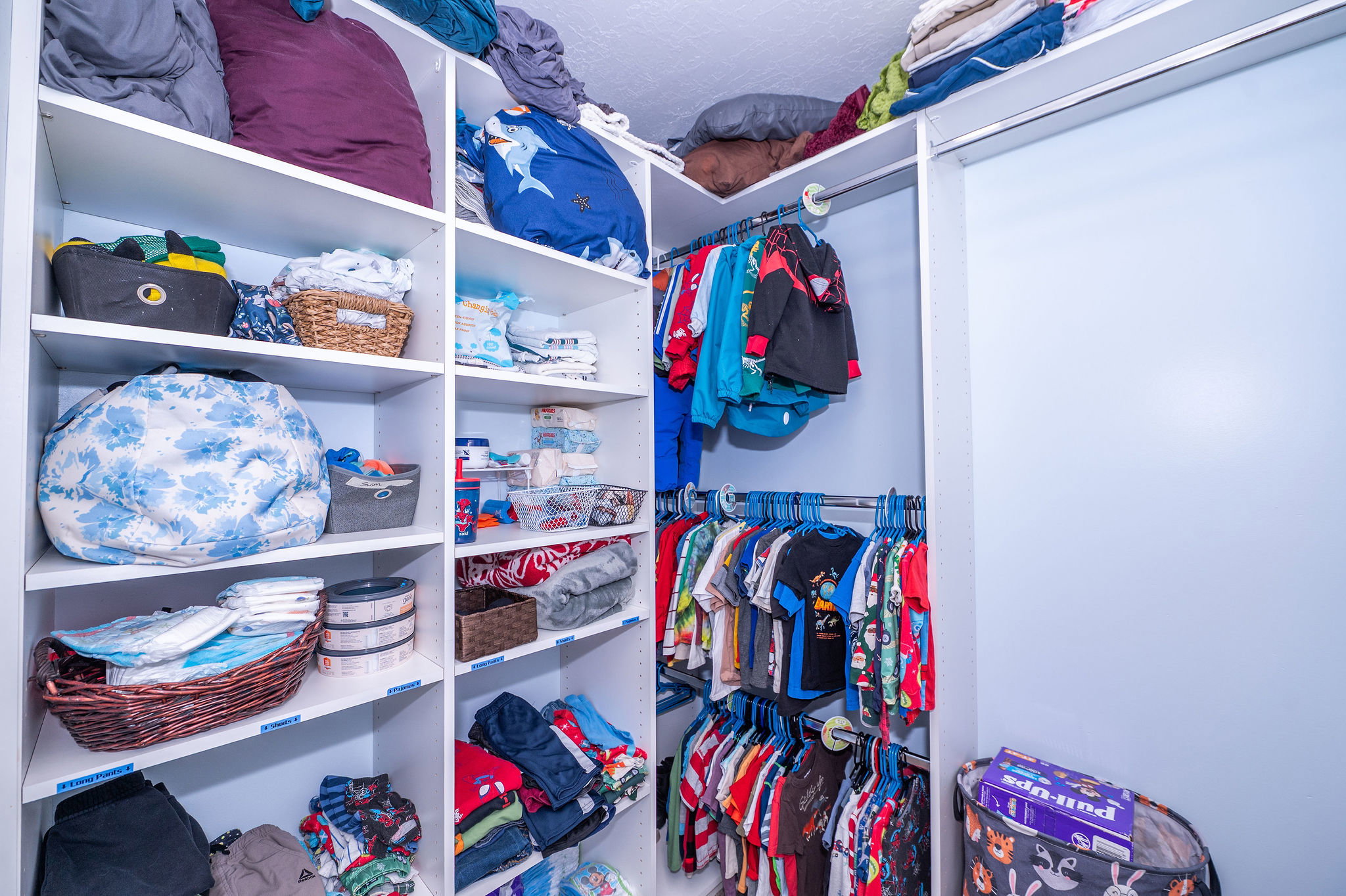 Built-in closet system featuring white shelving, multiple hanging rods, and a sliding panel door