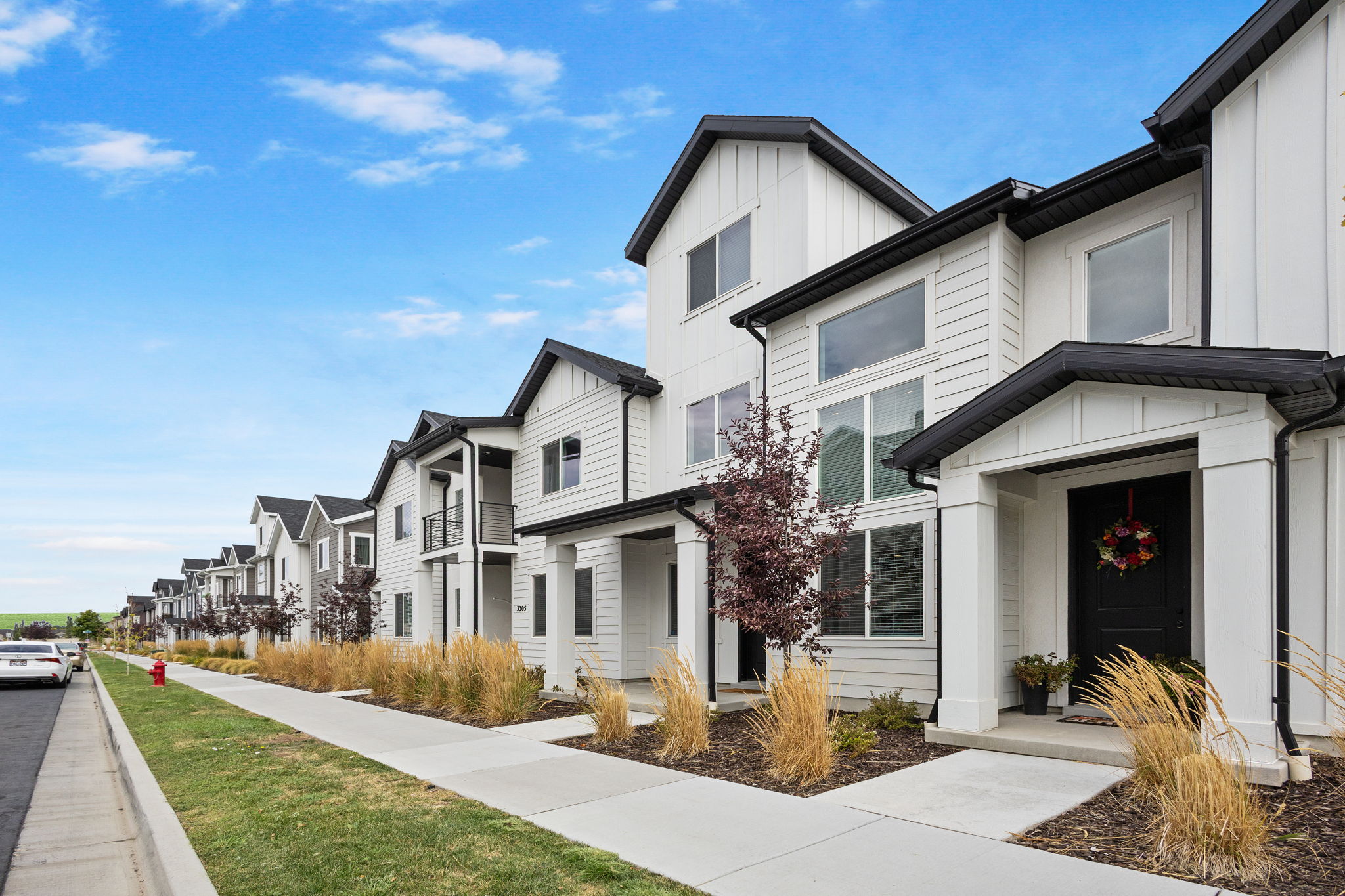 Modern townhome exterior featuring white board and batten siding, black trim, and a covered entry