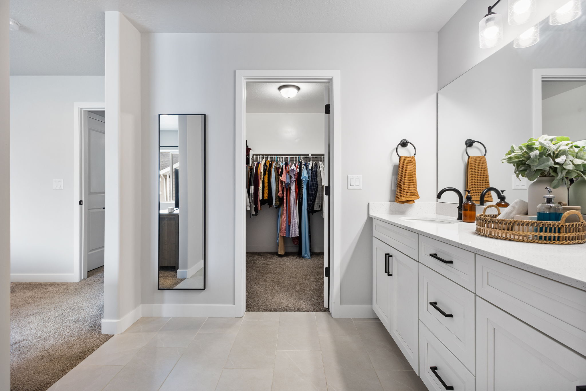 Dual-sink vanity with white cabinetry, quartz countertop, and black hardware