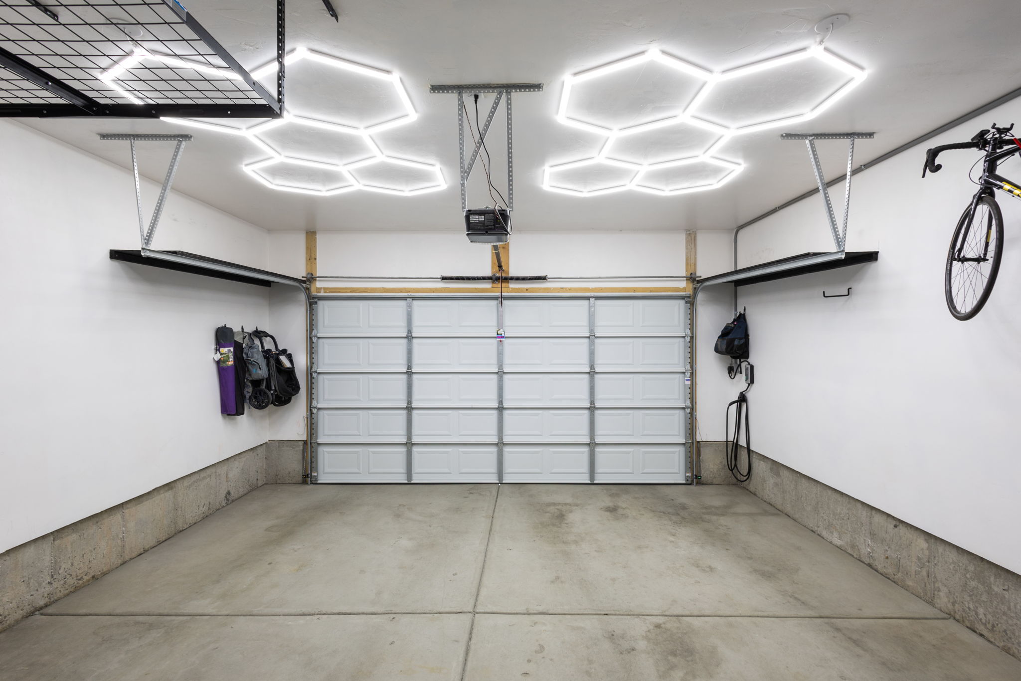 Spacious garage with a sectional overhead door, concrete flooring, and hexagonal ceiling light fixtures
