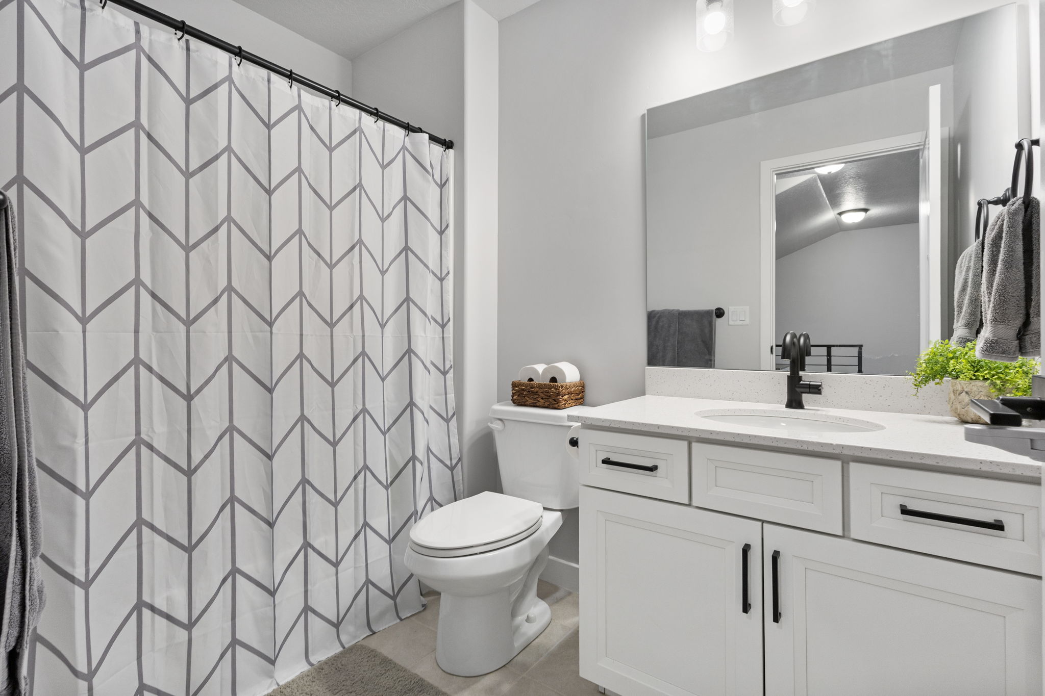 Bathroom vanity featuring a solid surface countertop, undermount sink, and matte black hardware