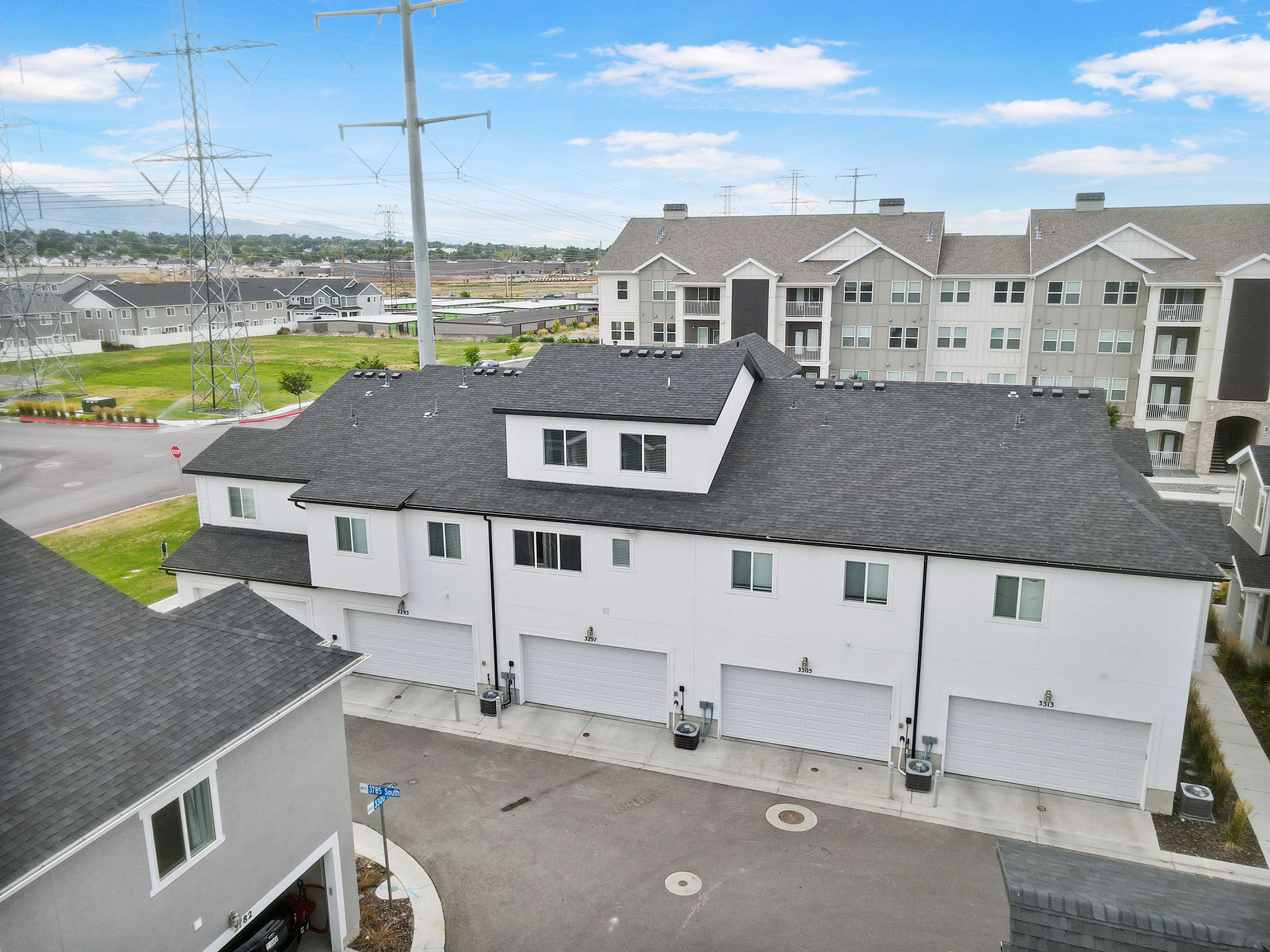 Townhome-style residences featuring a multi-car garage, white facade, and dark roofline