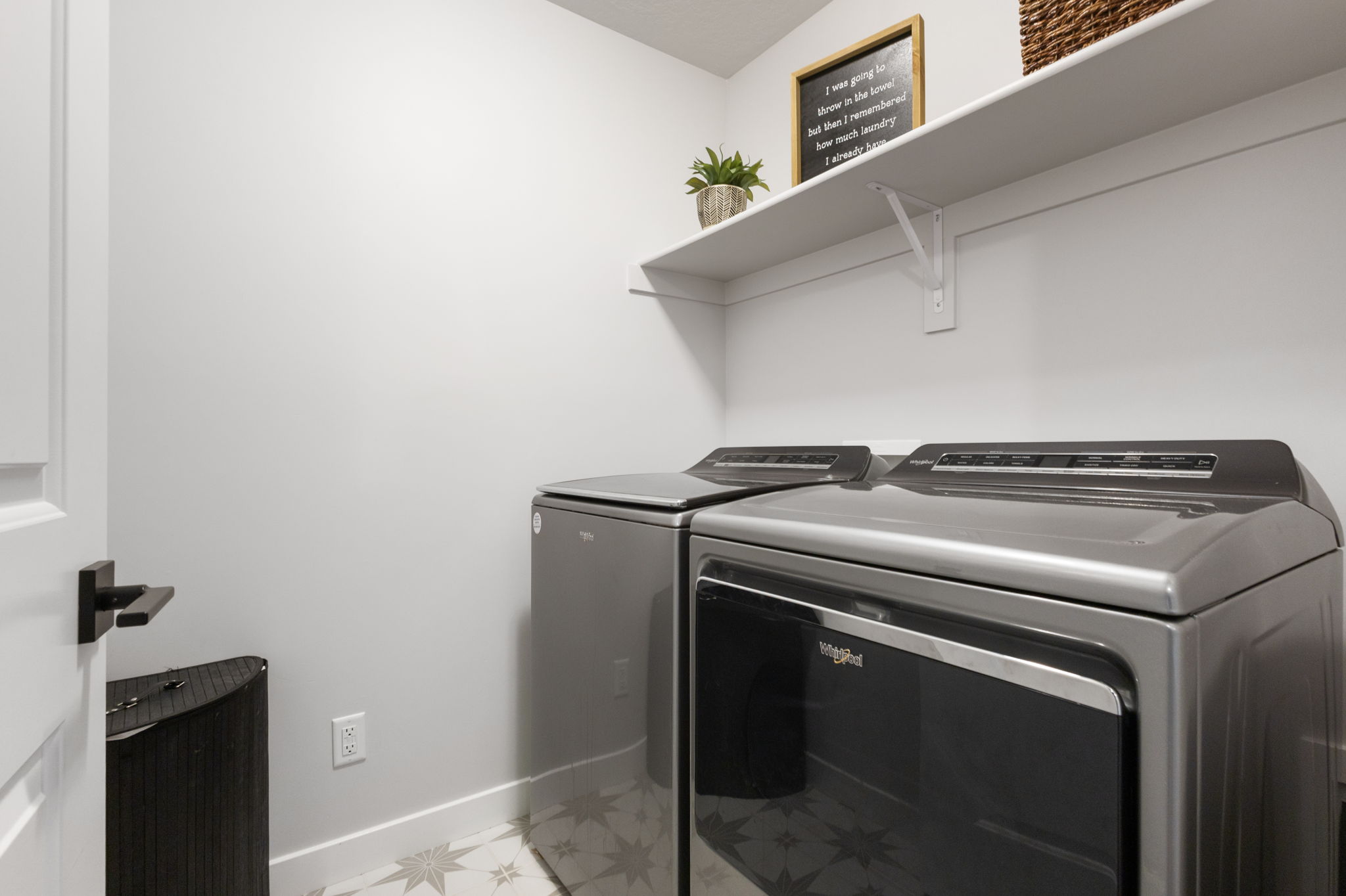 Dedicated utility space featuring patterned floor tile and a contrasting white baseboard