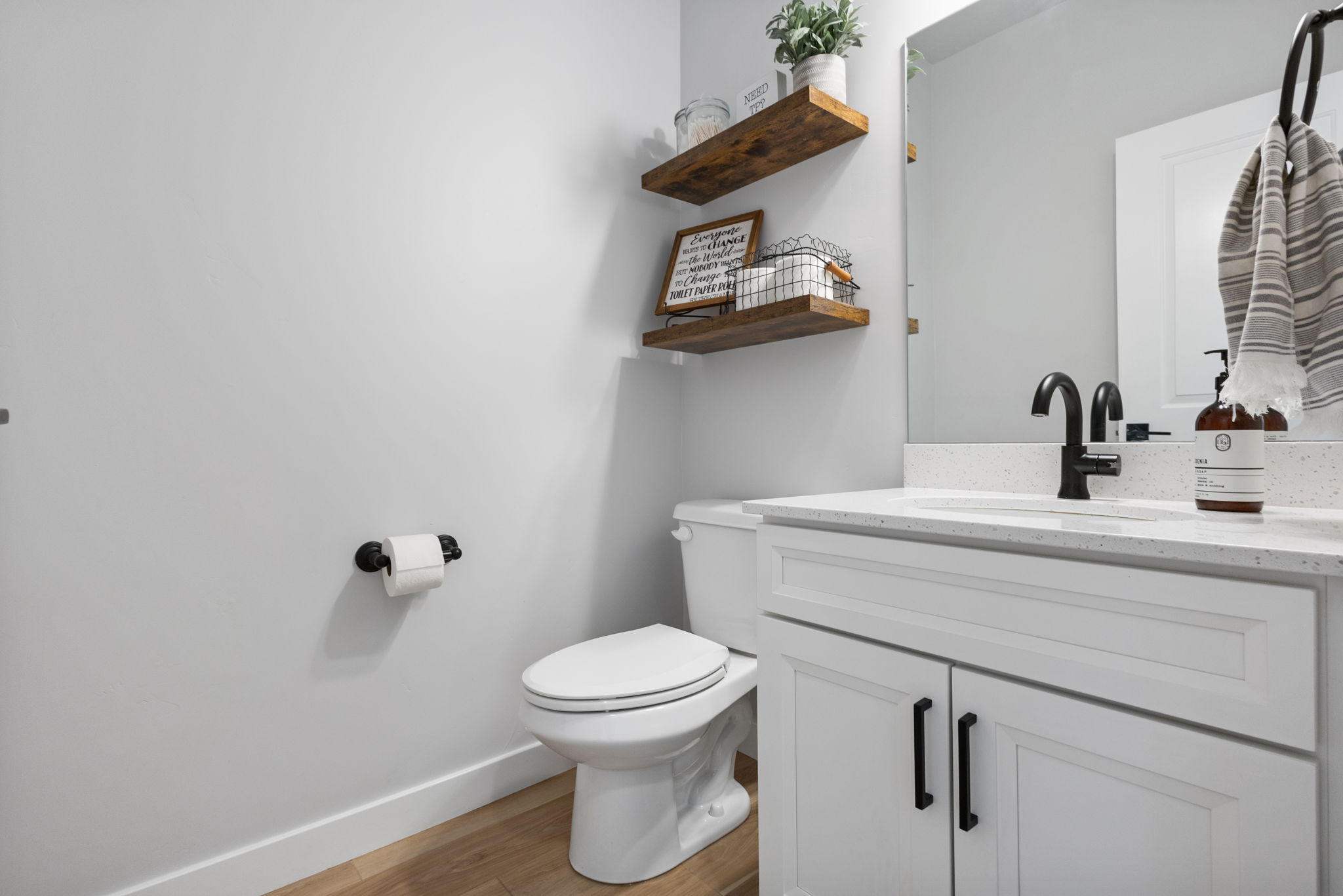 Bathroom vanity with white cabinetry, a speckled countertop, and a black gooseneck faucet