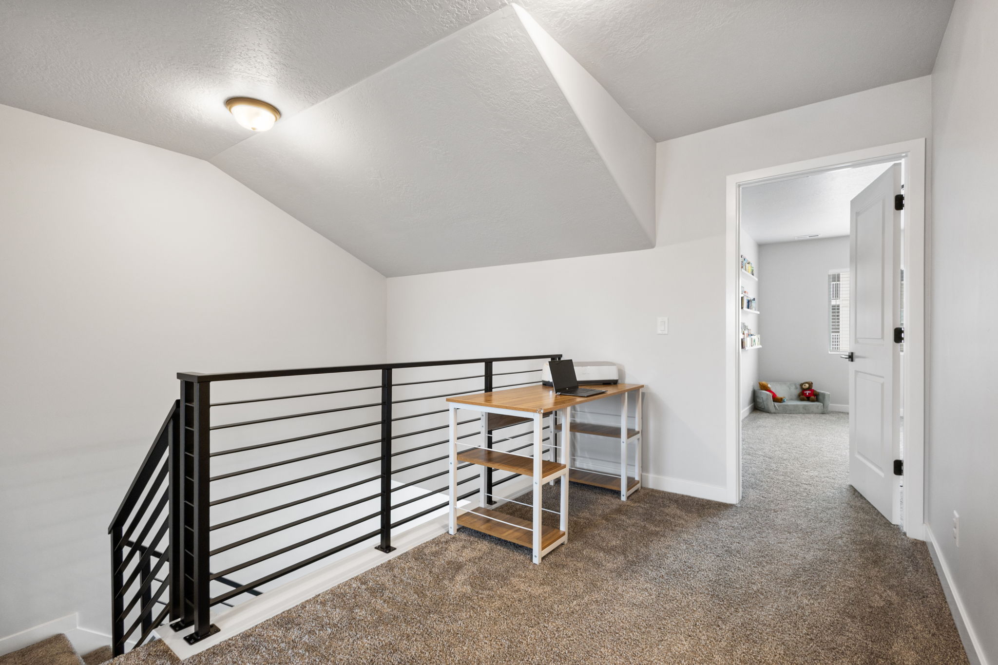 Carpeted loft area featuring a contemporary horizontal black metal railing overlooking the staircase