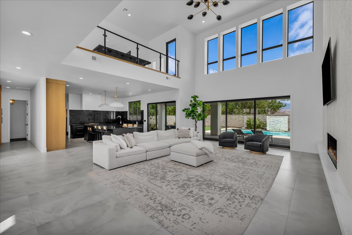Spacious living area featuring high ceilings, a loft overlooking the main space, and large windows