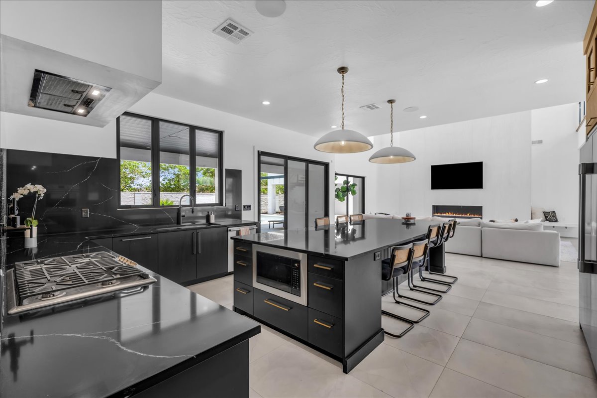 Modern kitchen featuring dark cabinetry, dark countertops with light veining, and a central island with integrated microwave