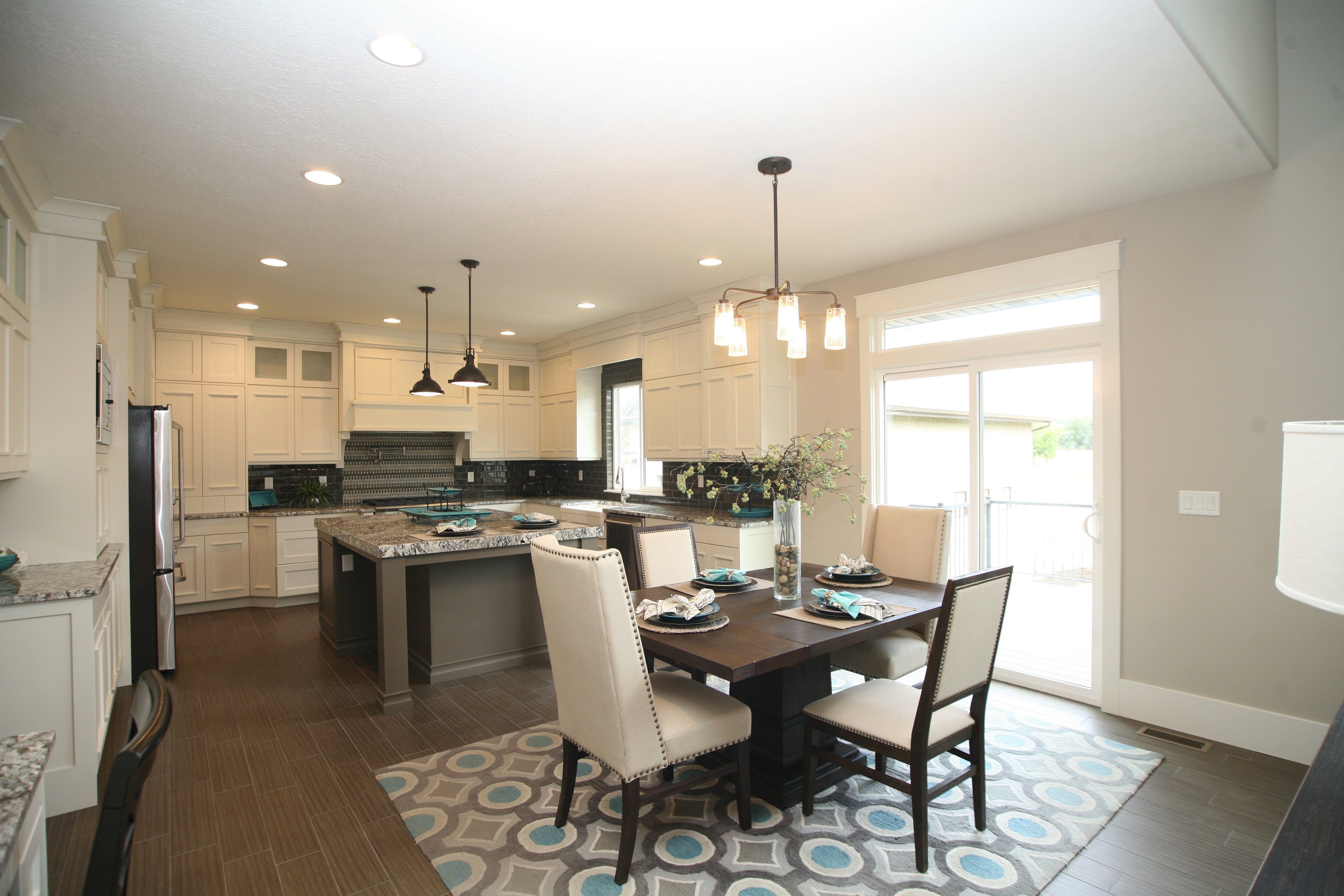 Spacious kitchen and dining area featuring light-toned cabinetry, granite countertops, and a large center island