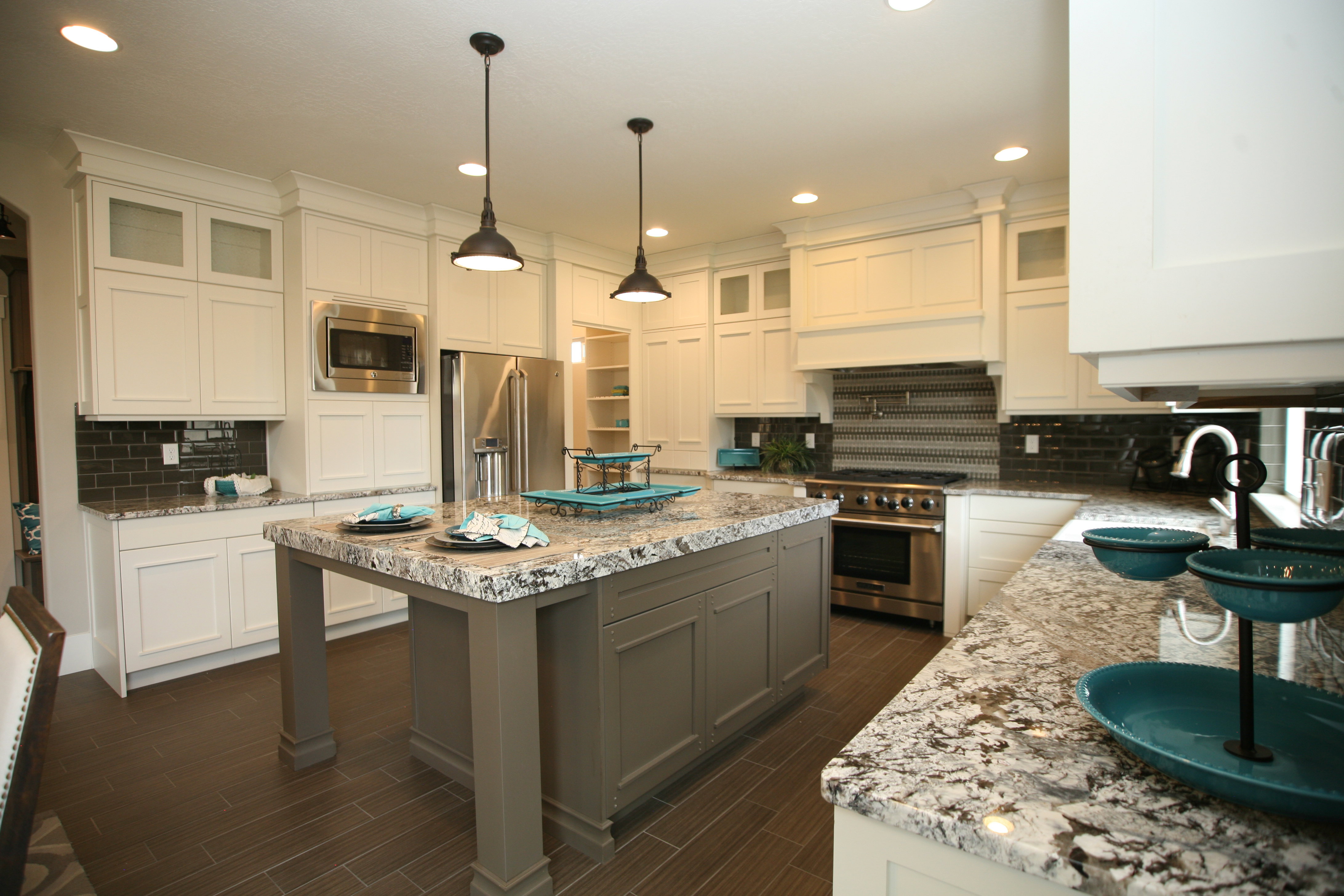 Kitchen featuring white cabinetry, wood-finish flooring, stainless steel appliances, a multi-tonal backsplash, and granite countertops