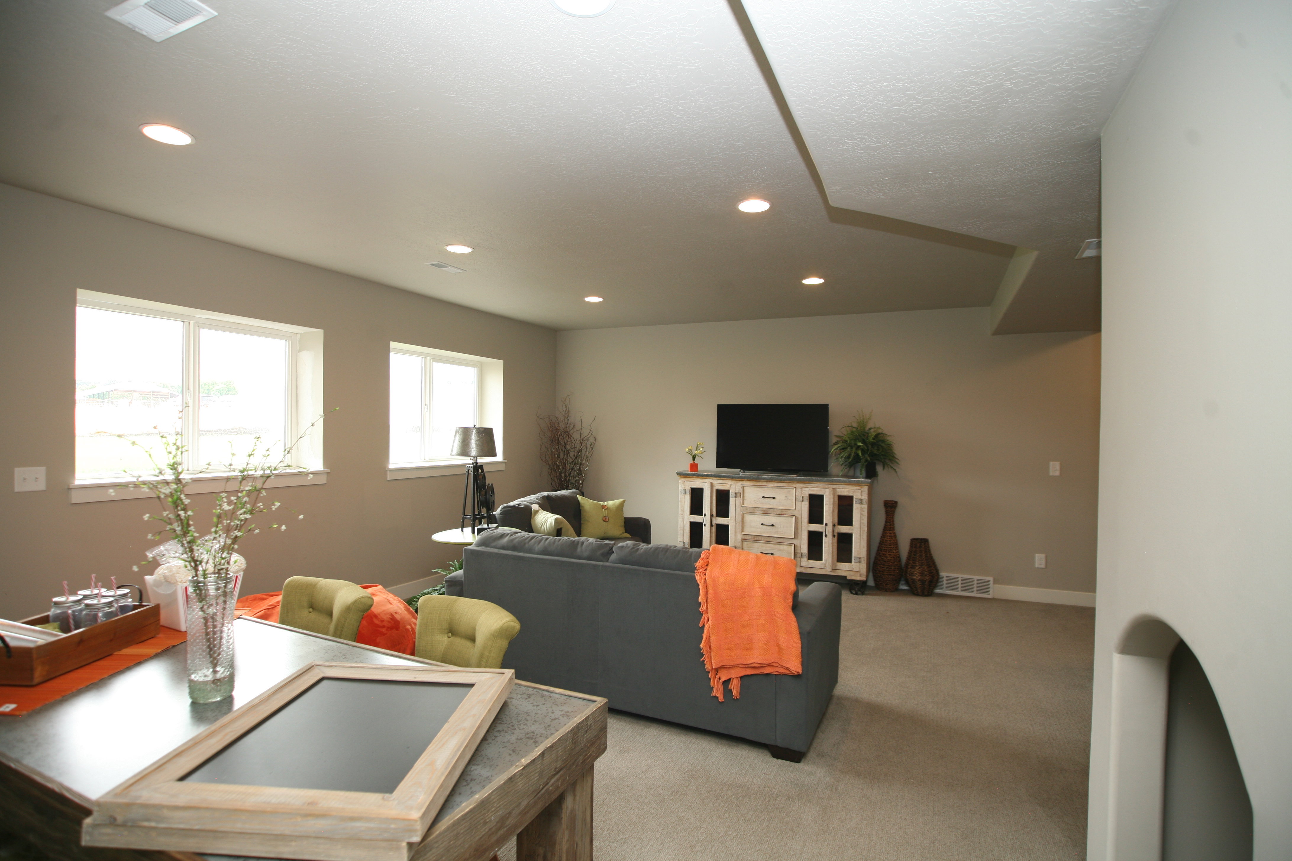 Spacious living area featuring neutral walls, recessed lighting, carpet flooring, multiple windows providing natural light, and taller basement ceiling.