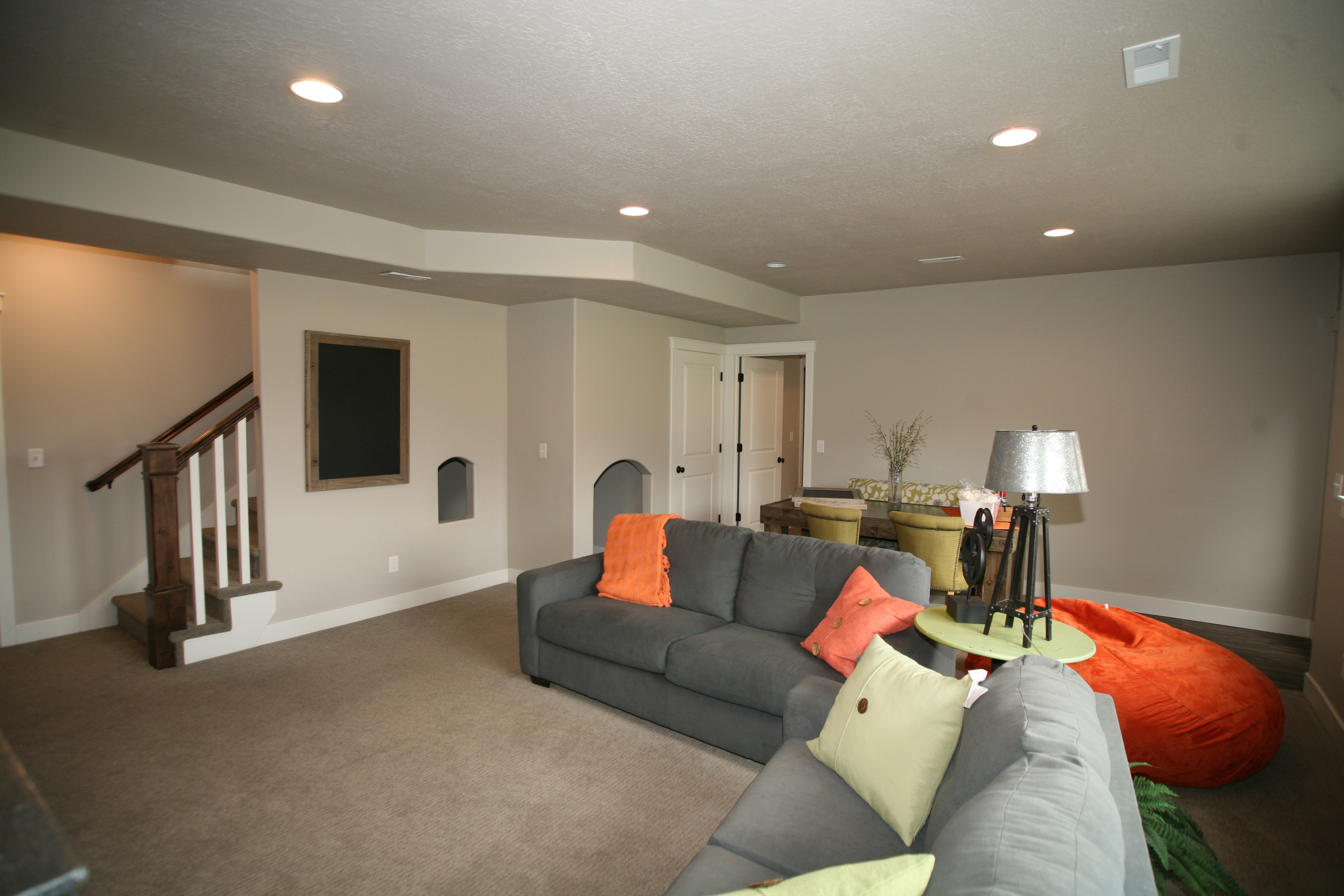 Spacious room featuring recessed lighting, a neutral color palette, built-in wall niches, and a stairway with wood newel posts and handrails, this home features a great kid cave under the stairs.
