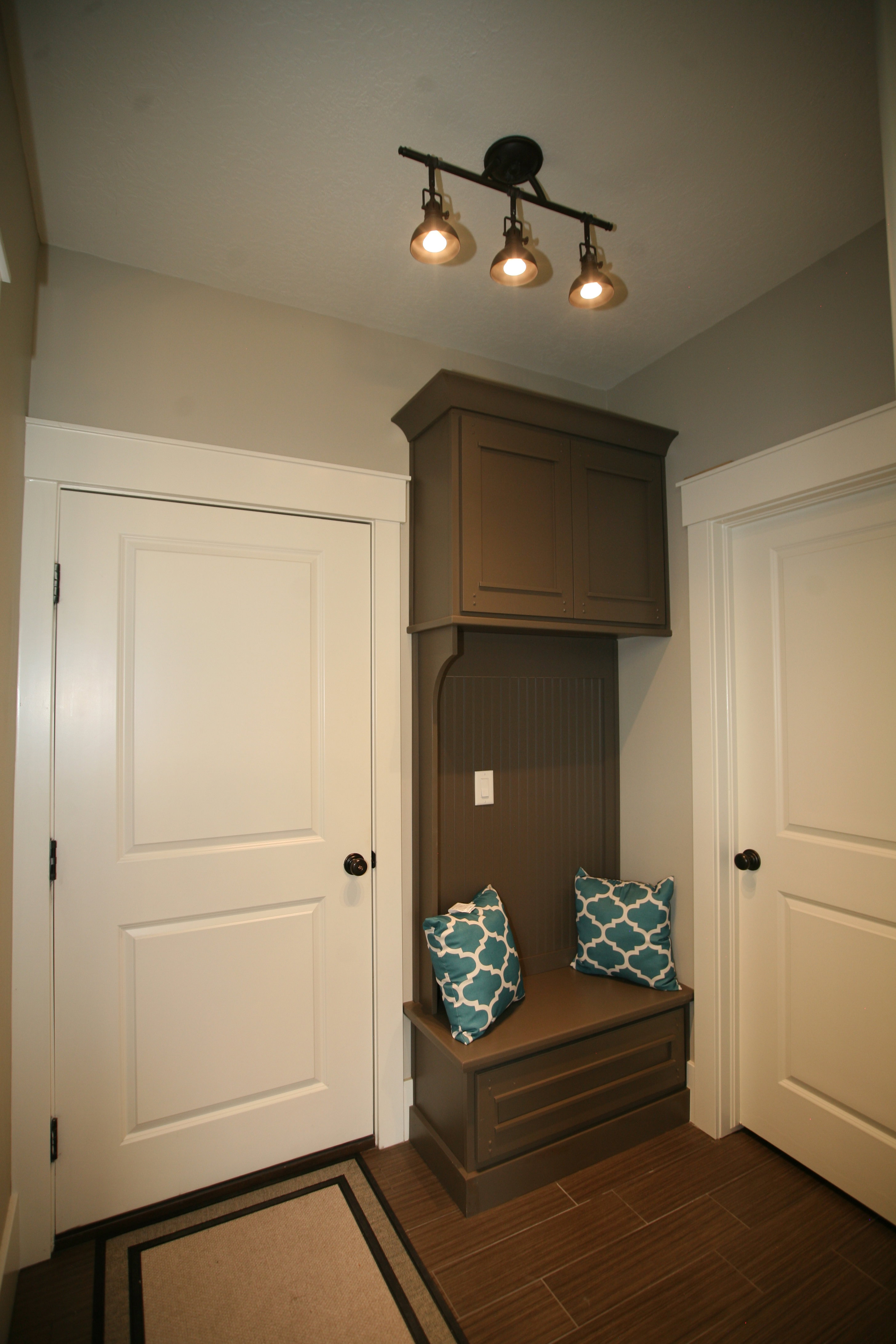 Custom built-in entryway bench with overhead cabinetry and beadboard backing