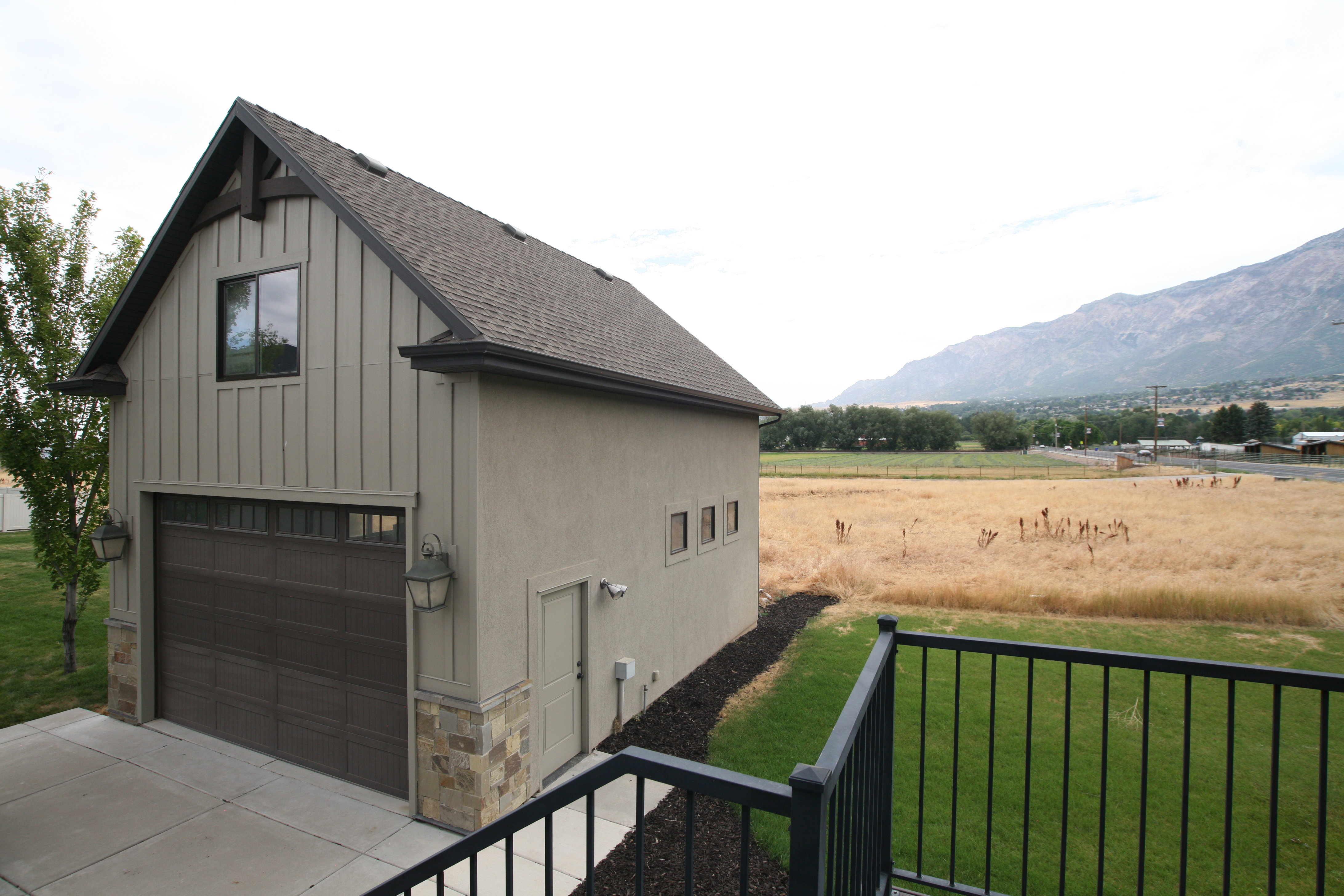 Detached two-car garage featuring a dark wood-finish door, board and batten siding, and stone accents