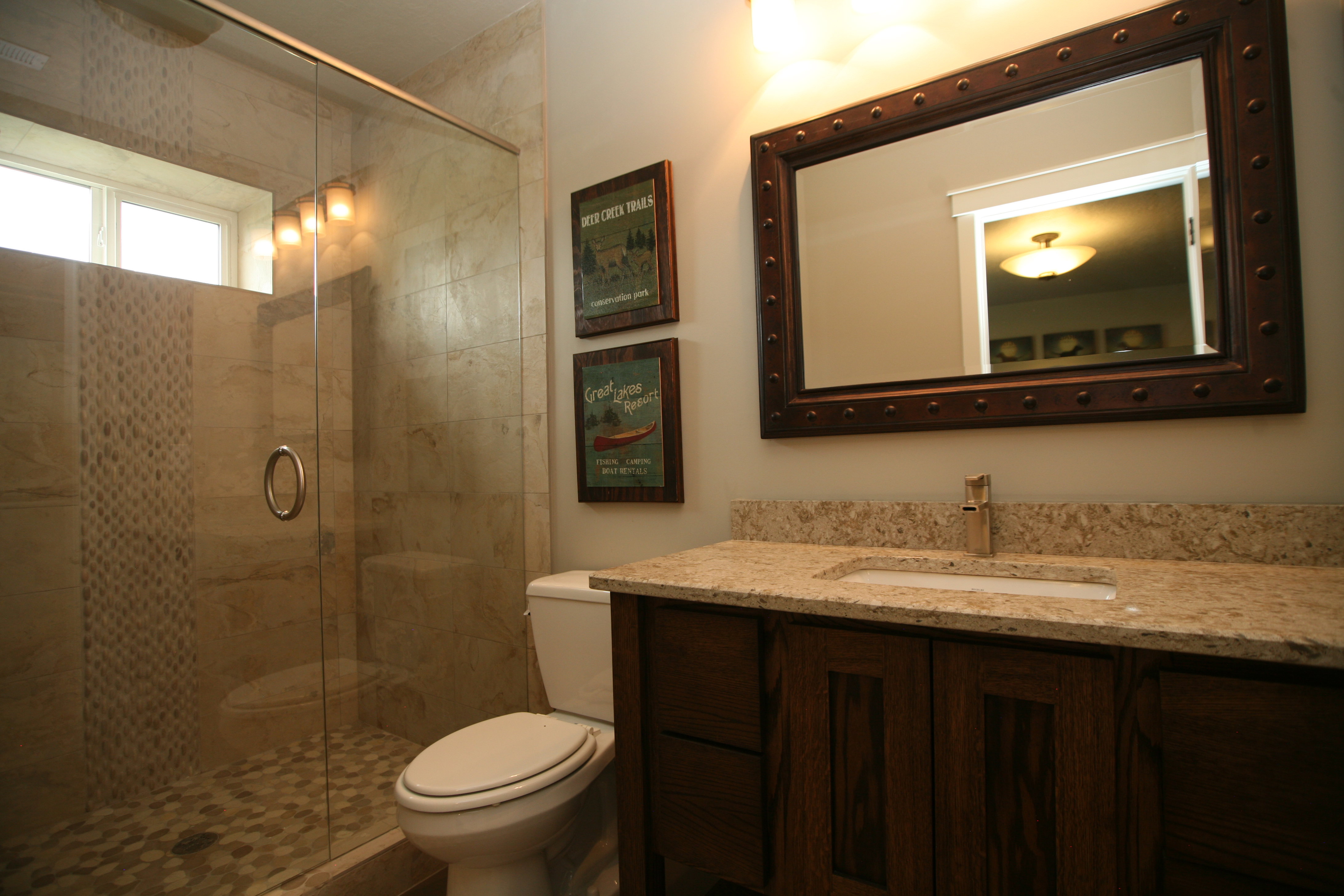 Full bathroom featuring a glass-enclosed shower with tiled walls and pebble-finish flooring, great dedicated bathroom to guest suite