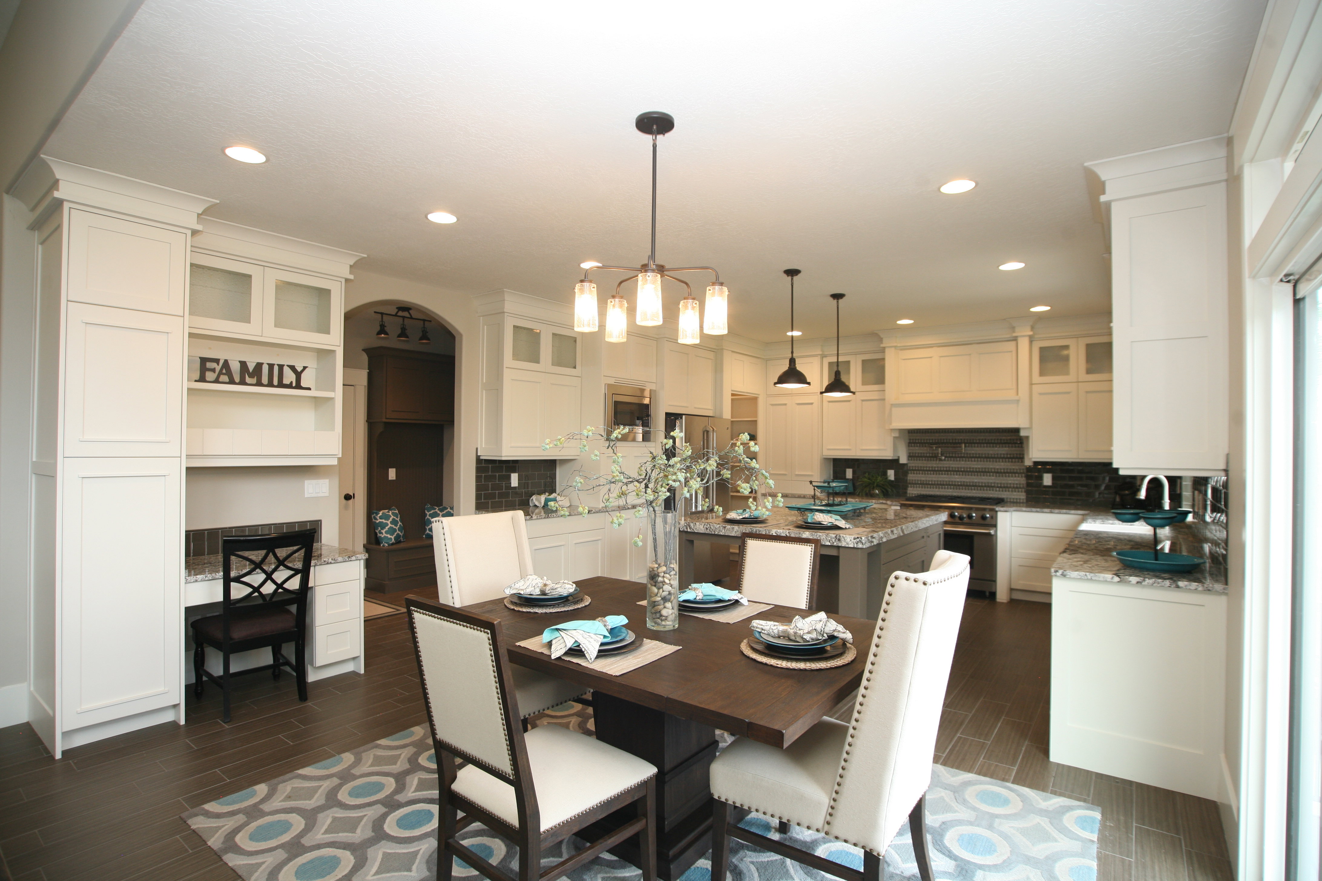 Spacious kitchen featuring an extended island, white cabinetry, dark wood-finish flooring, recessed lighting, and a built-in desk area