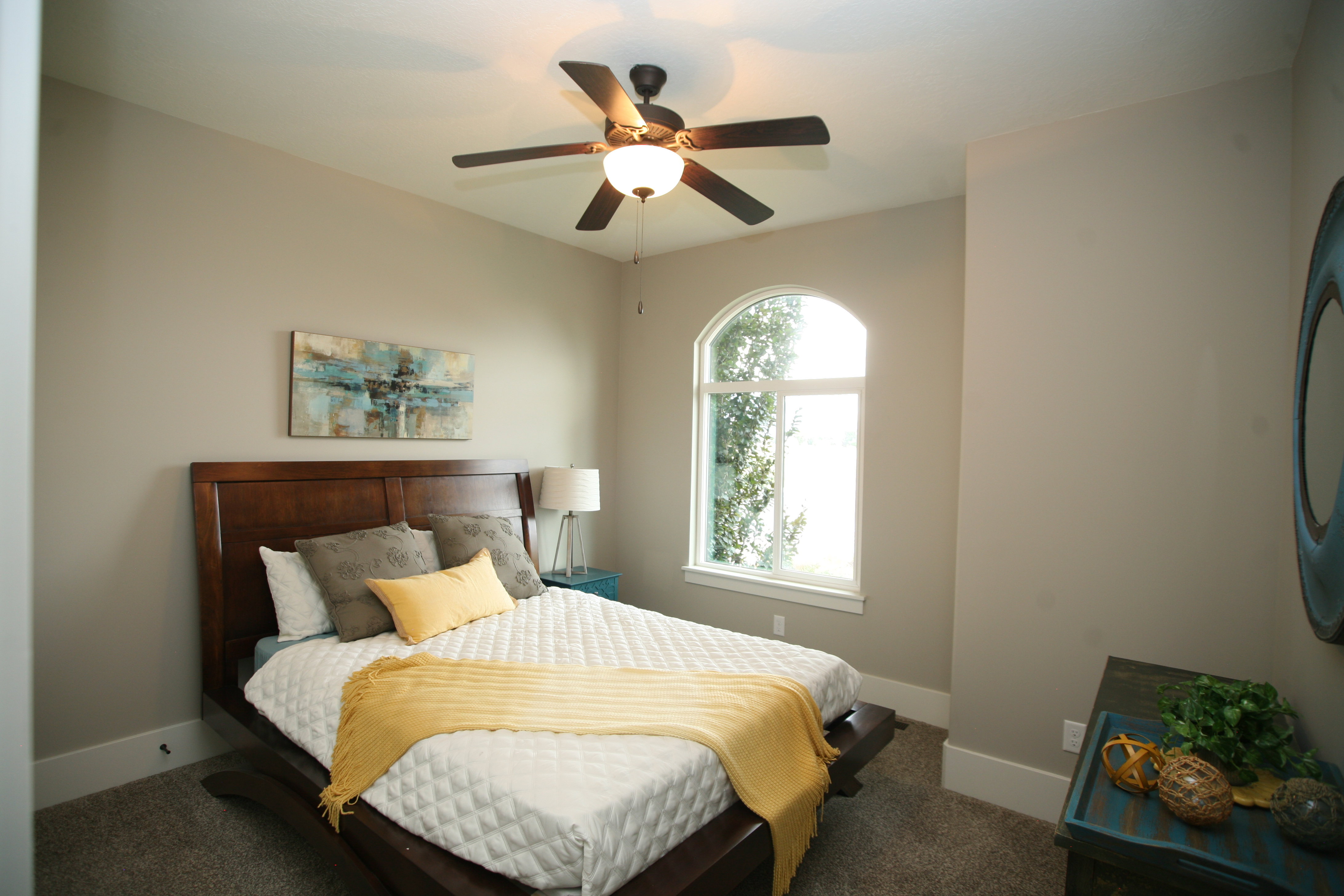 Room featuring an arched window, ceiling fan with integrated lighting, and neutral wall paint