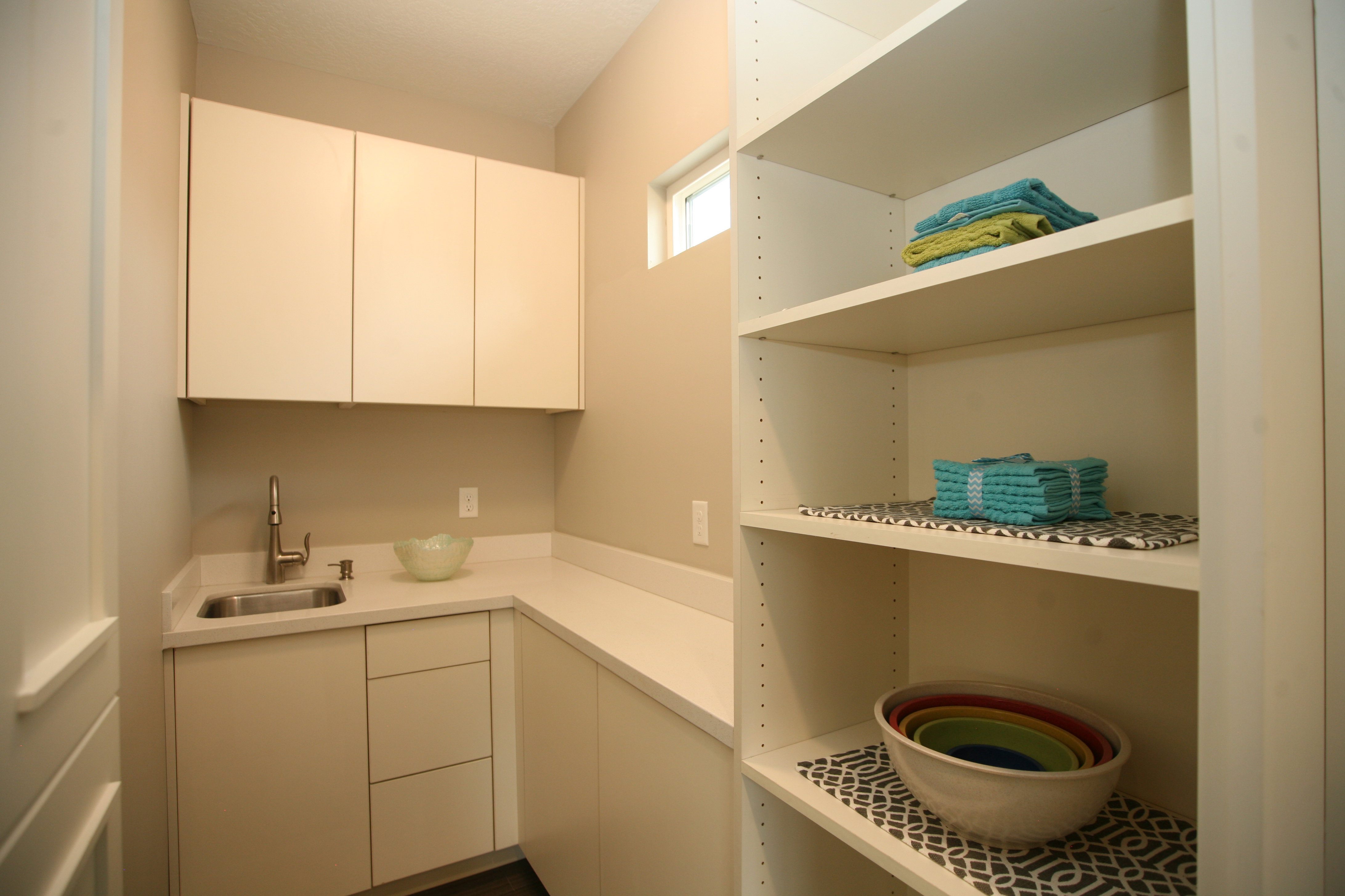 Pantry with built-in shelving, white cabinetry, integrated sink, and white countertops