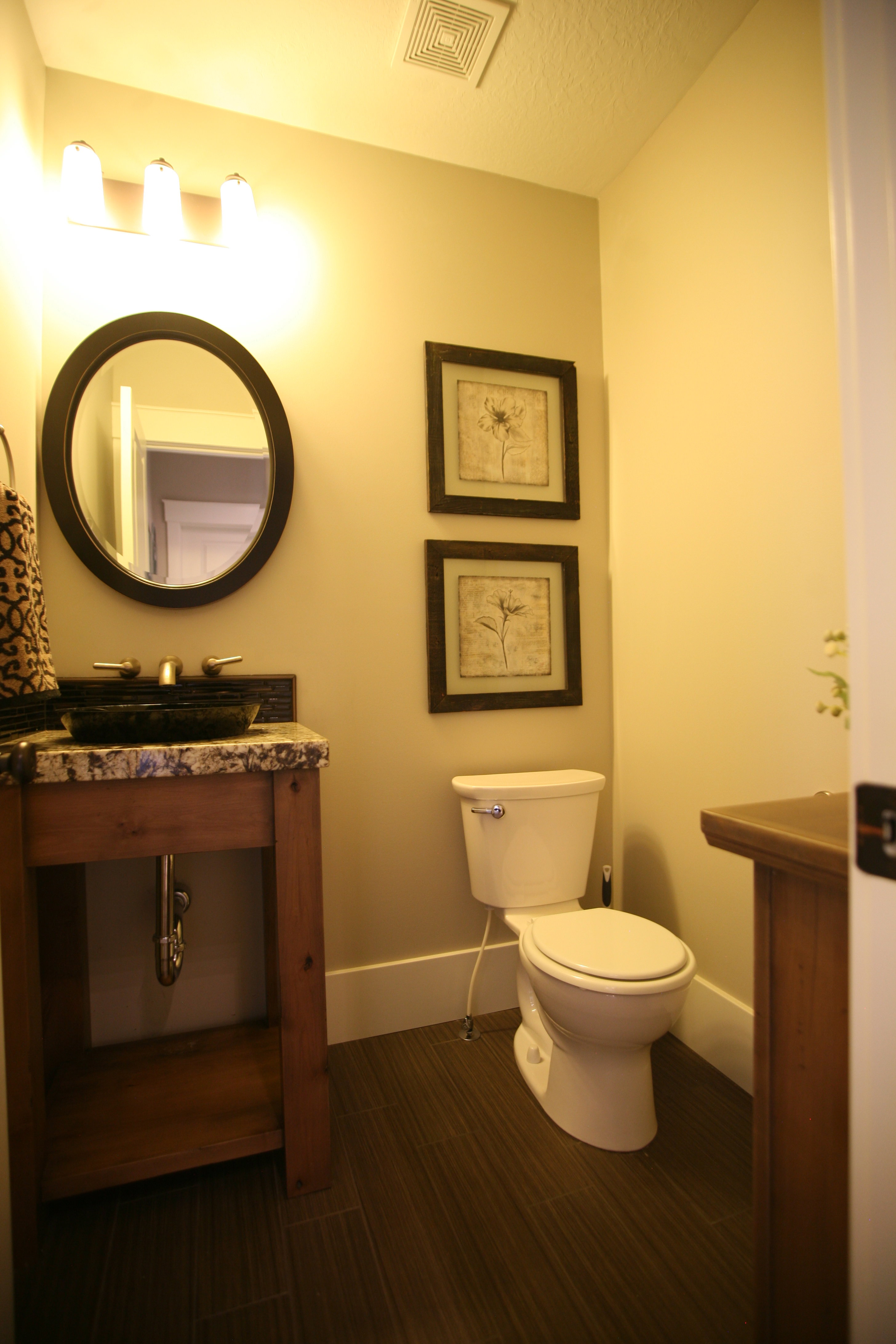 Powder room featuring a rustic wood vanity with a vessel sink, a granite countertop, and dark wood-finish flooring