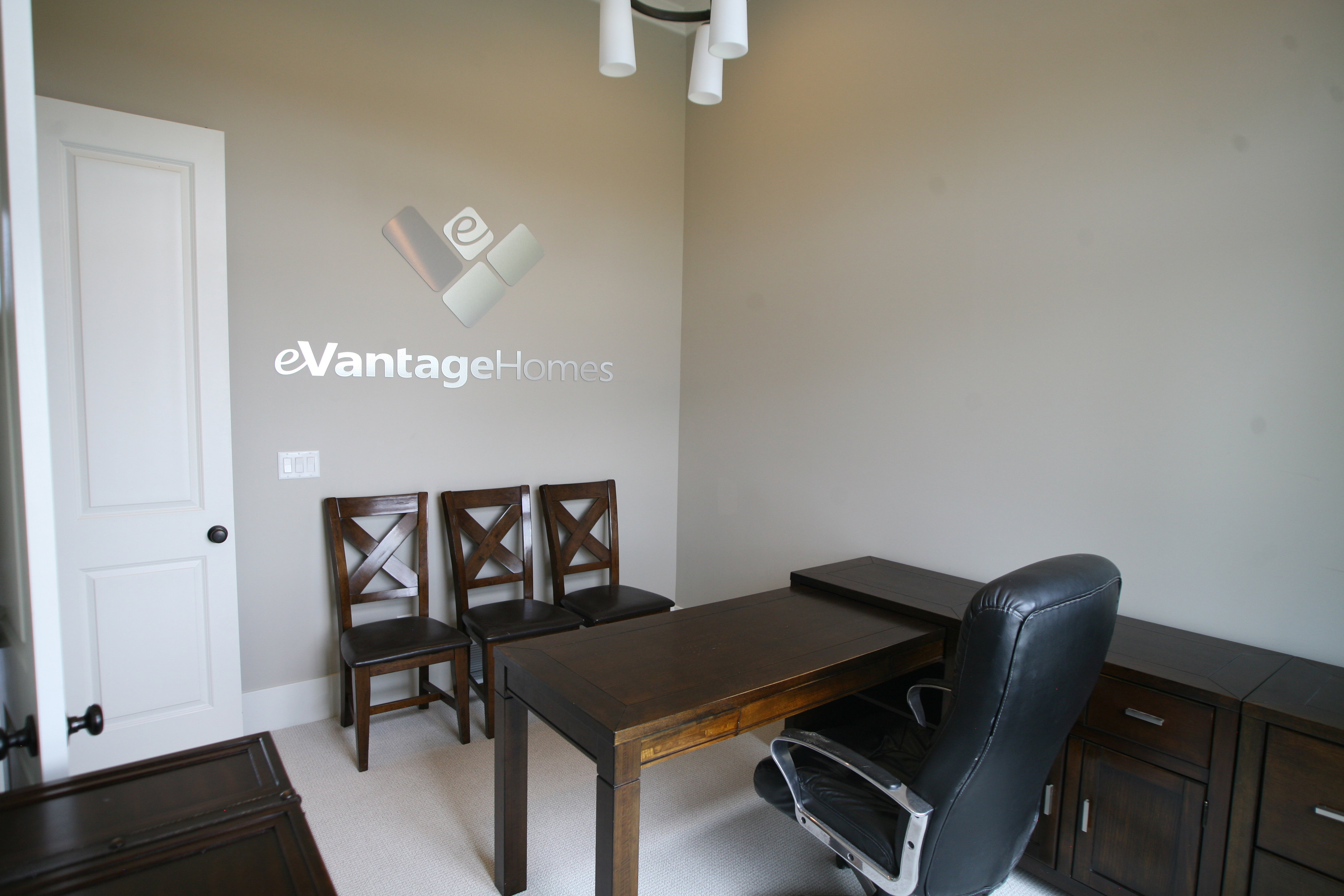 Spacious room with light neutral wall paint, white panel door with dark hardware, and light-colored carpet flooring