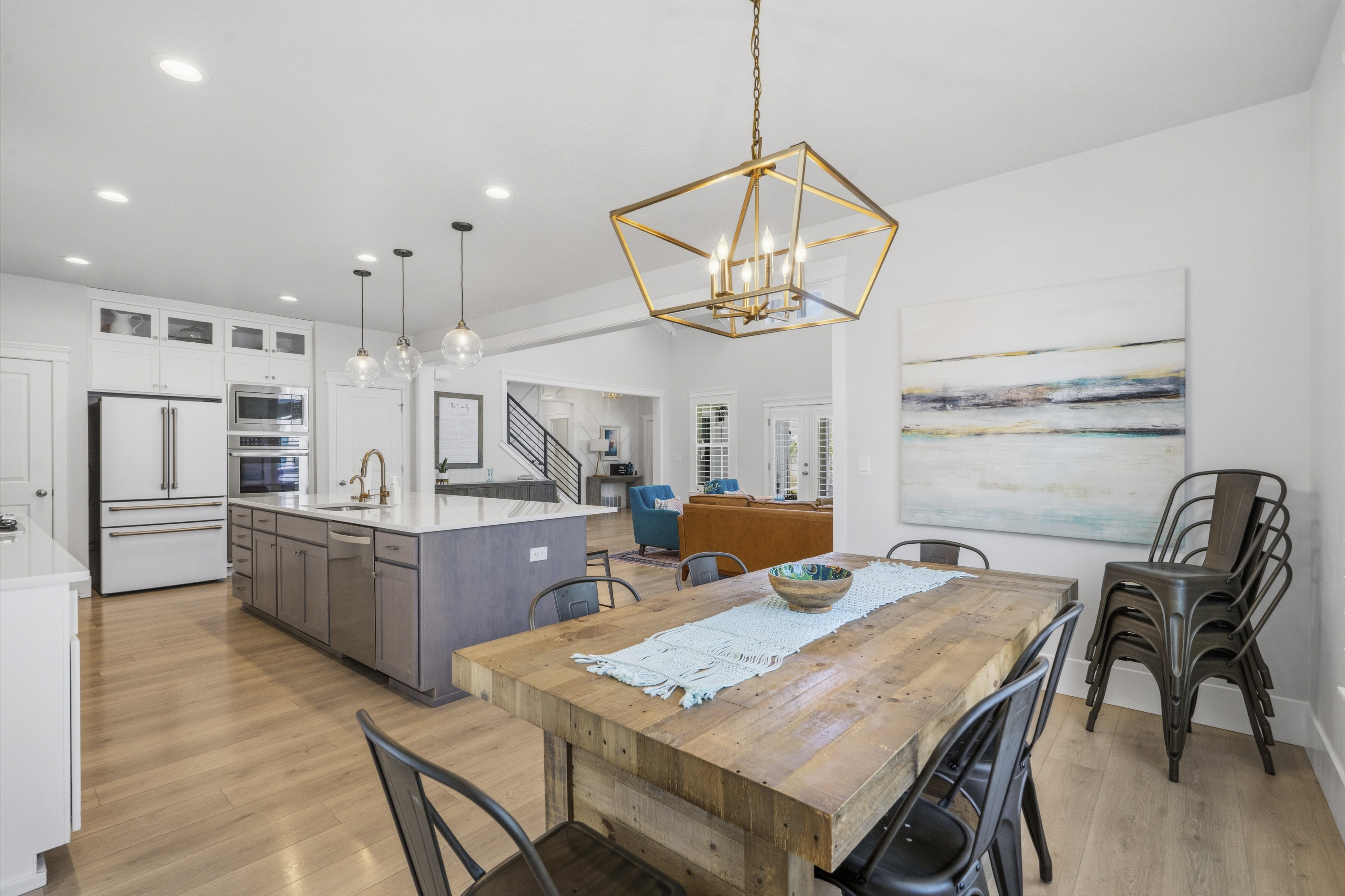 Open-concept dining area with wood-finish flooring, a contemporary brass chandelier, and recessed lighting