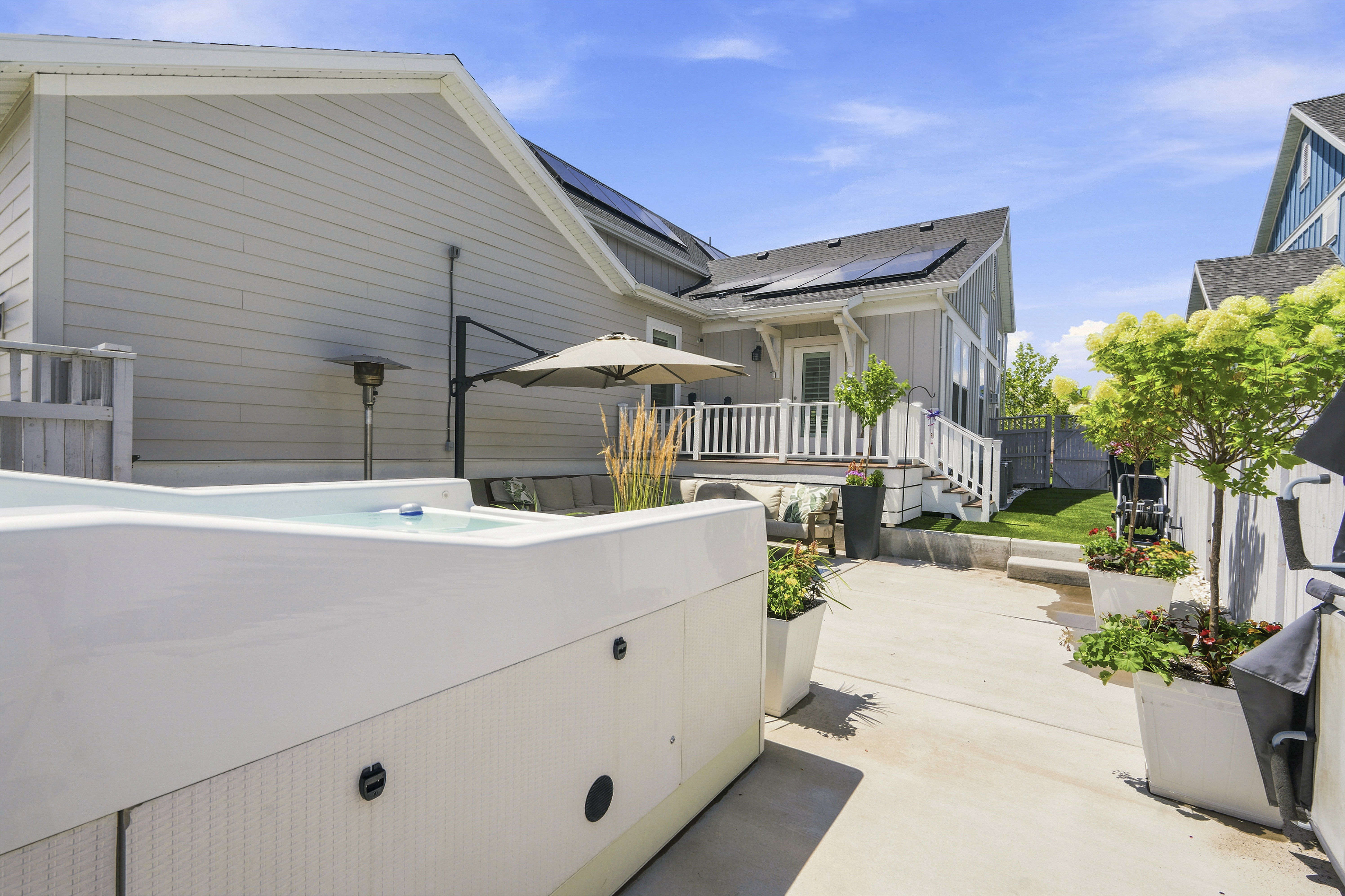 Backyard featuring a built-in spa, concrete patio, and elevated deck with white railing