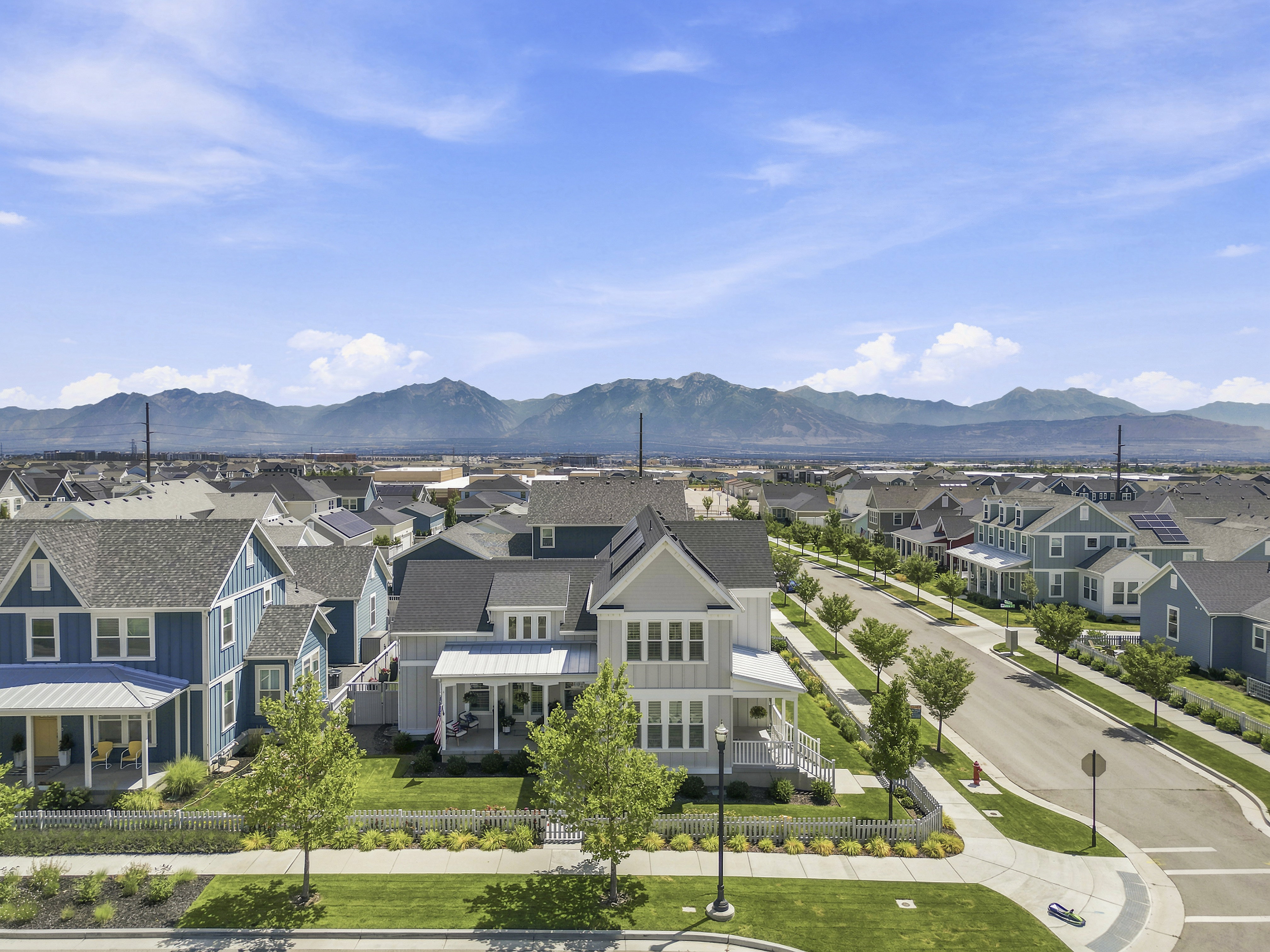 Modern residential neighborhood featuring a tree-lined street and mountain backdrop