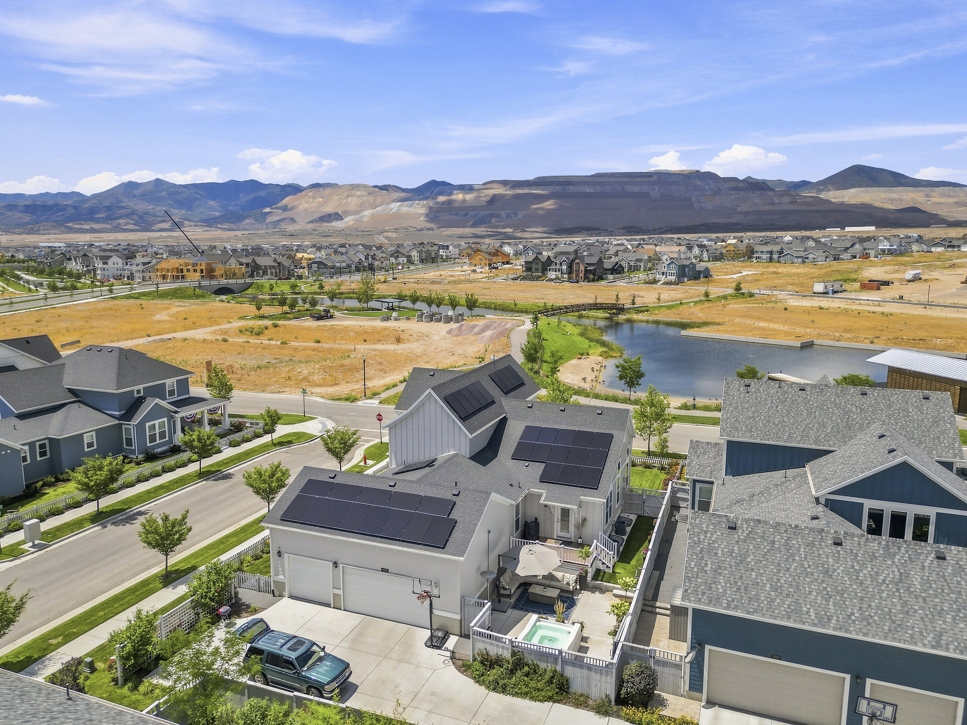 Modern residential property featuring rooftop solar panels, a two-car garage, and a private backyard patio with a built-in hot tub