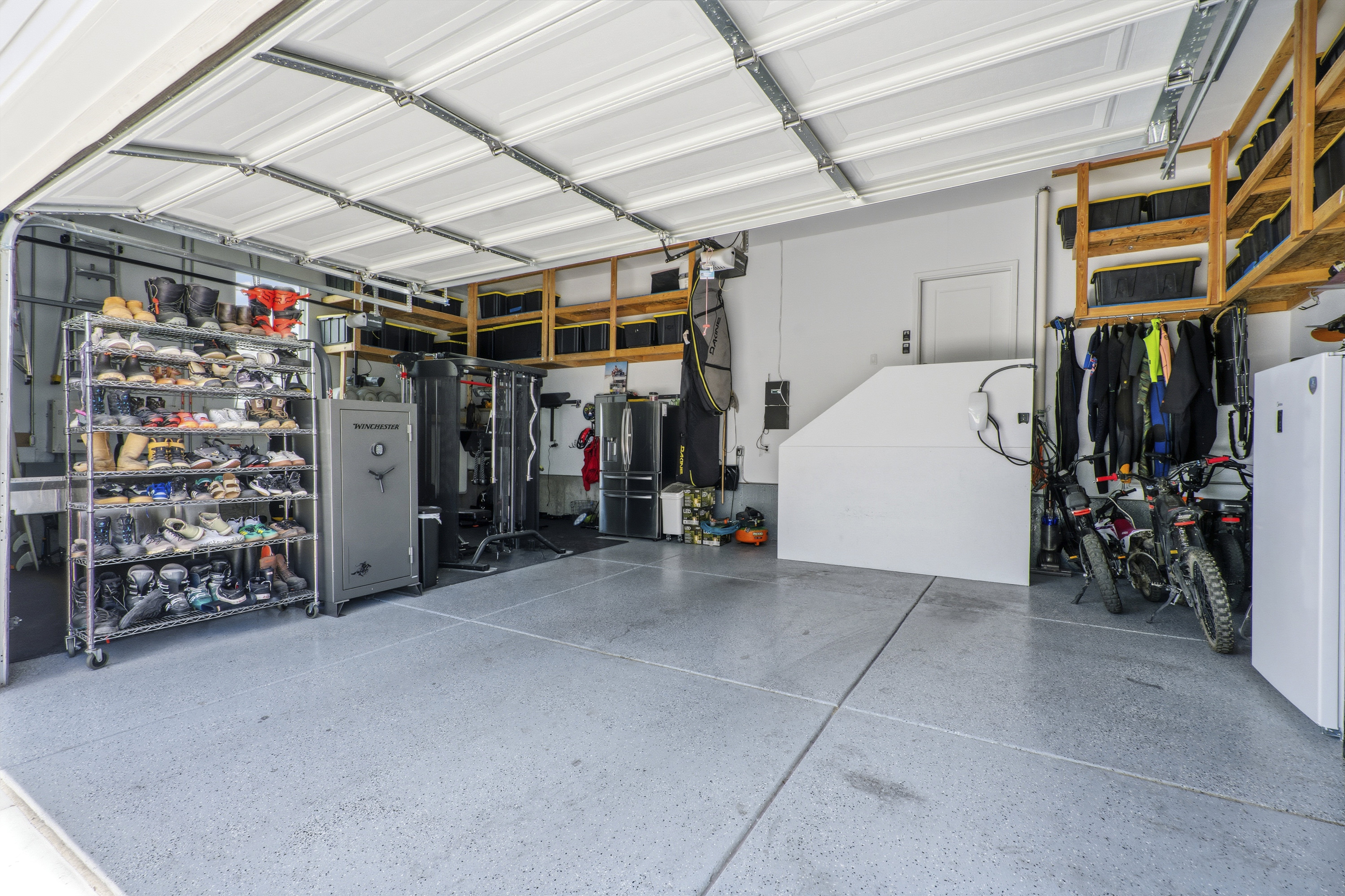 Spacious garage featuring a durable epoxy floor coating, extensive overhead wood shelving, and a prominent interior door