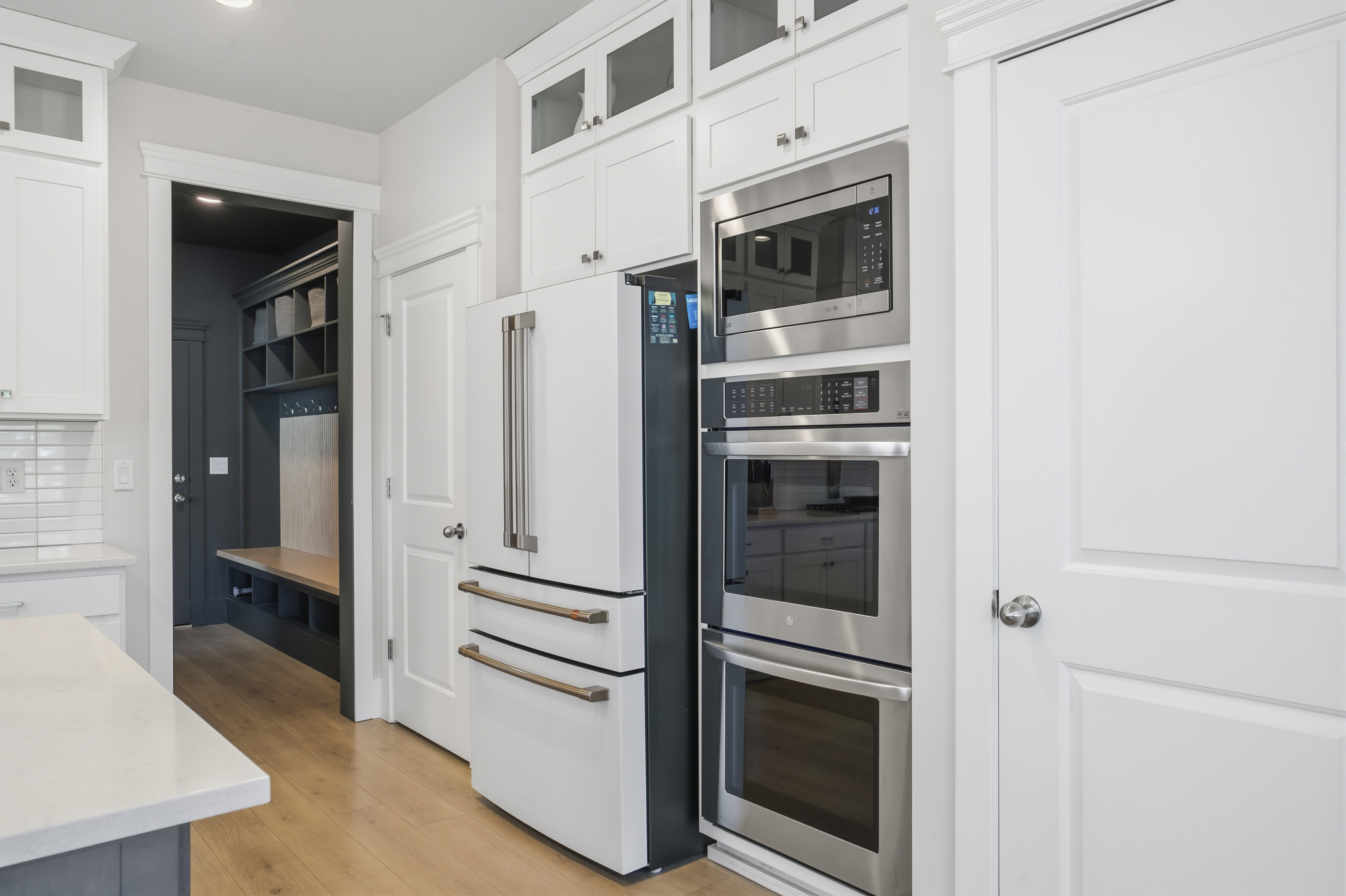 Kitchen featuring white cabinetry, built-in stainless steel appliances including a microwave and double oven, and wood-finish flooring