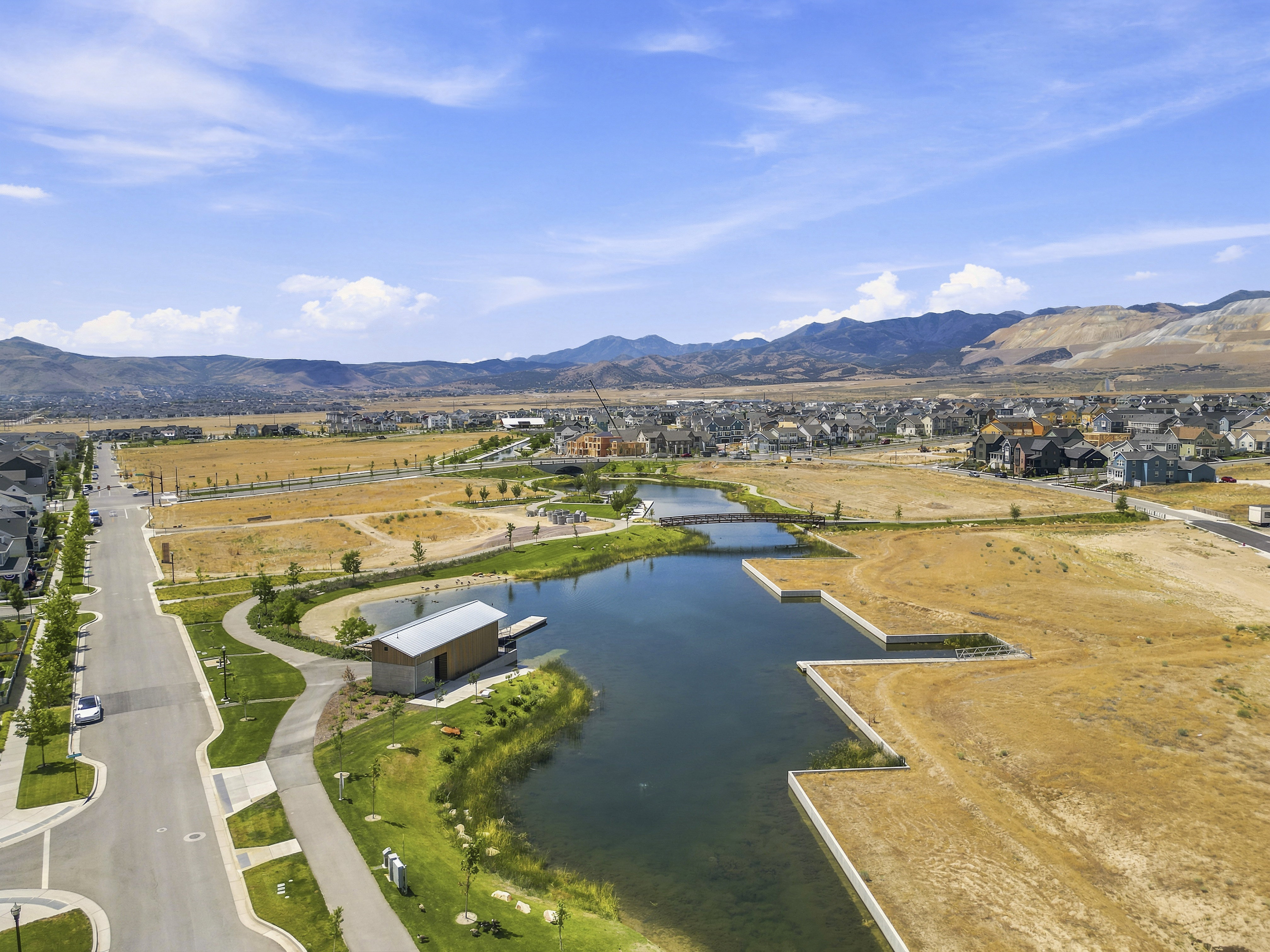 Community lake with a boat house, a pedestrian bridge, and surrounding green spaces