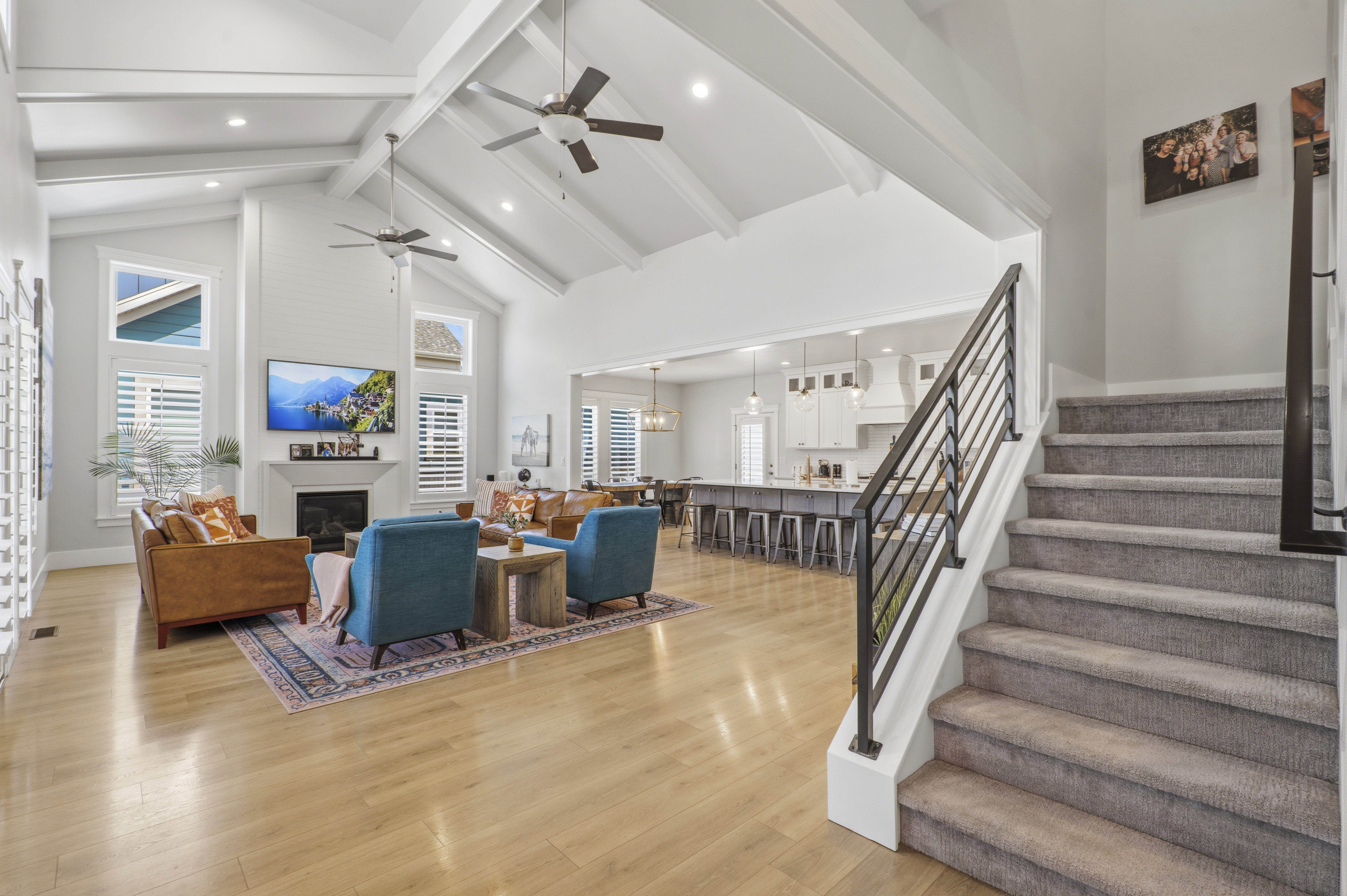 Vaulted ceilings with exposed beams, light wood-finish flooring, and a fireplace with a mantel