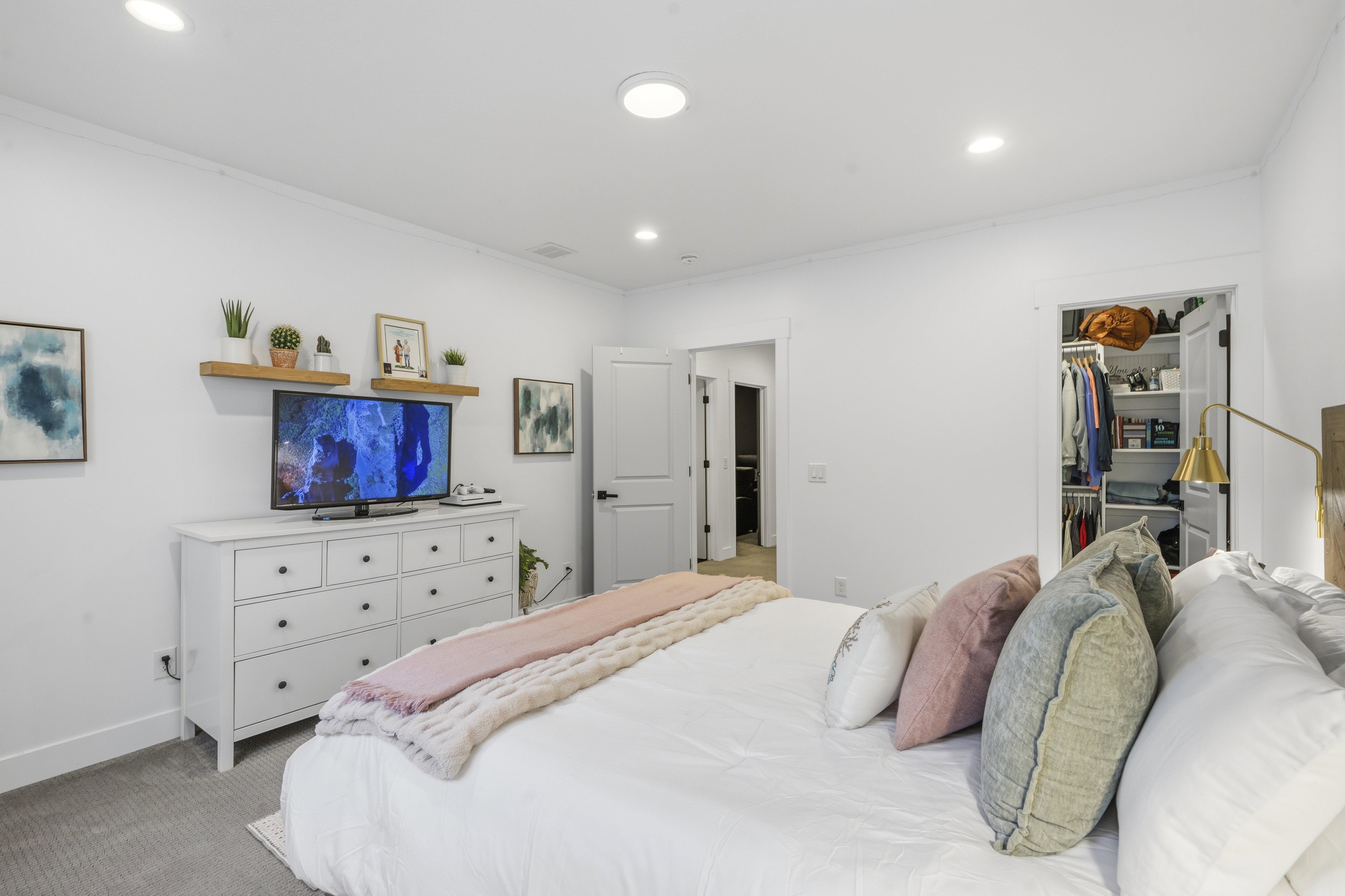 Recessed lighting illuminates the room, featuring a built-in closet with shelving and a secondary doorway