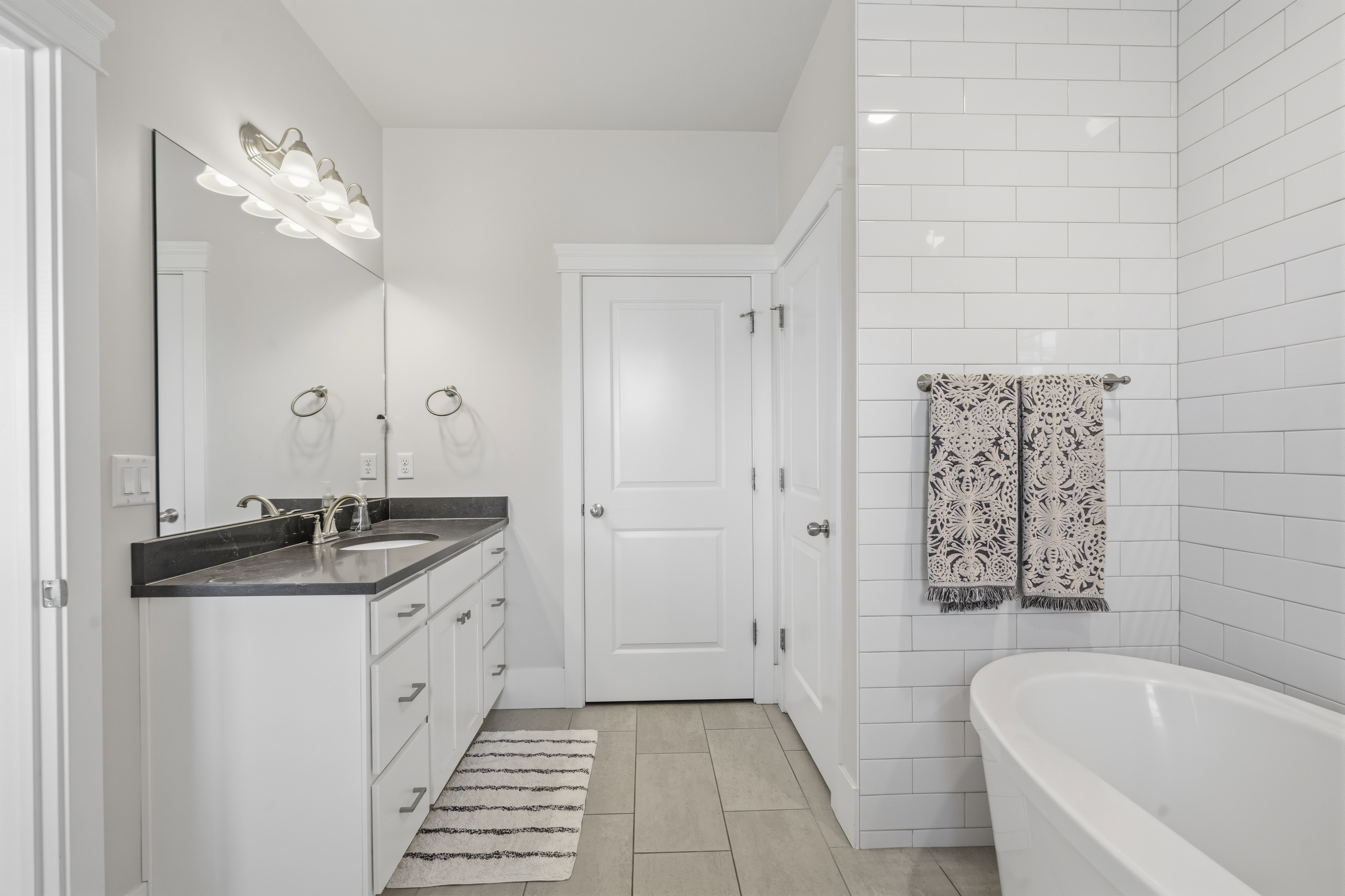 Bathroom with a freestanding soaking tub and white subway tile surround