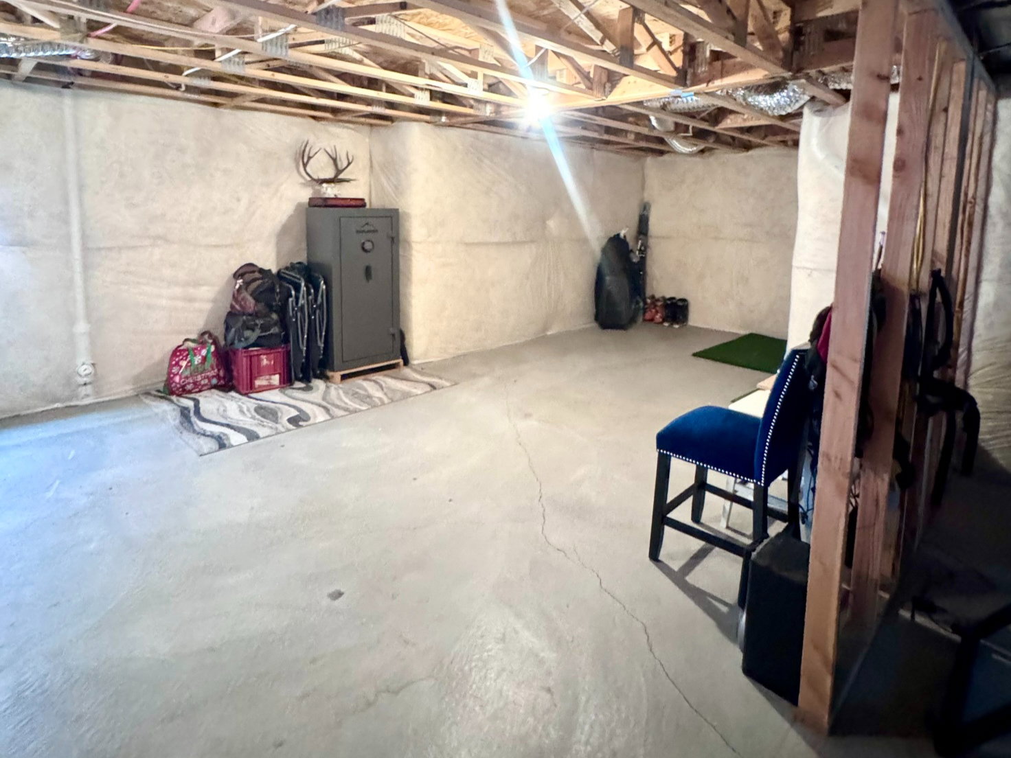 Unfinished basement featuring exposed wood ceiling joists and concrete flooring