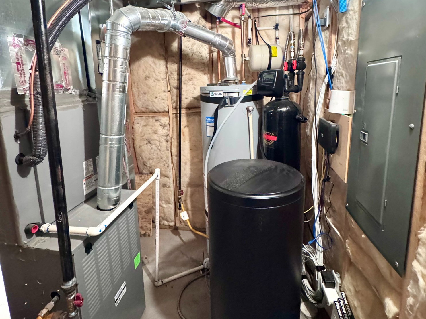 Utility area featuring a water heater, furnace, water softener, and electrical panel