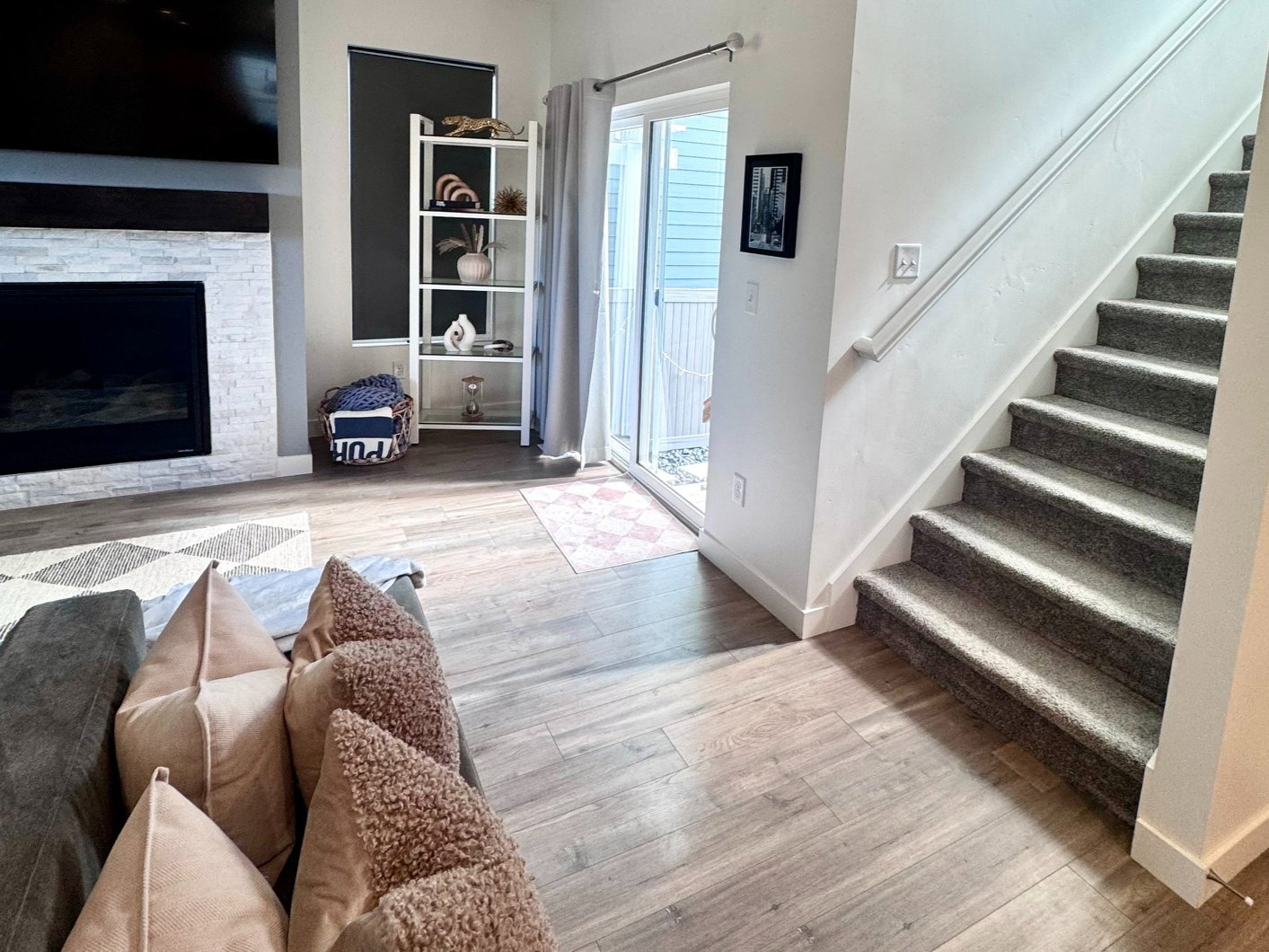 Living area featuring wood-finish flooring, a fireplace with a light-toned stone surround, recessed lighting, and a sliding glass door