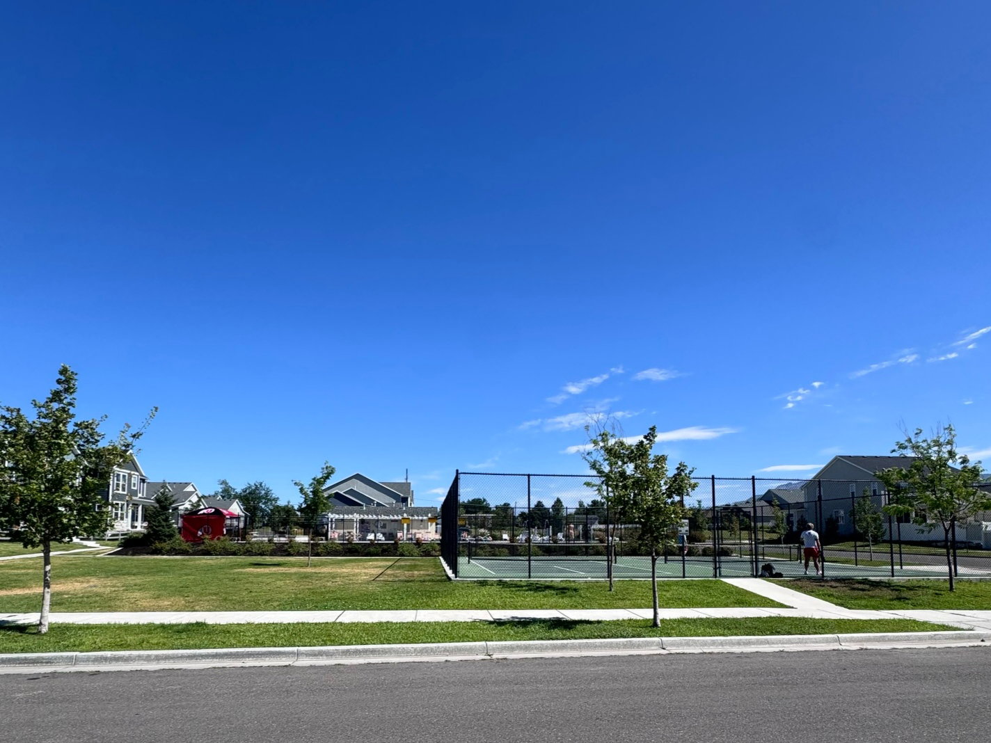 Neighborhood tennis court with surrounding green space and residential structures