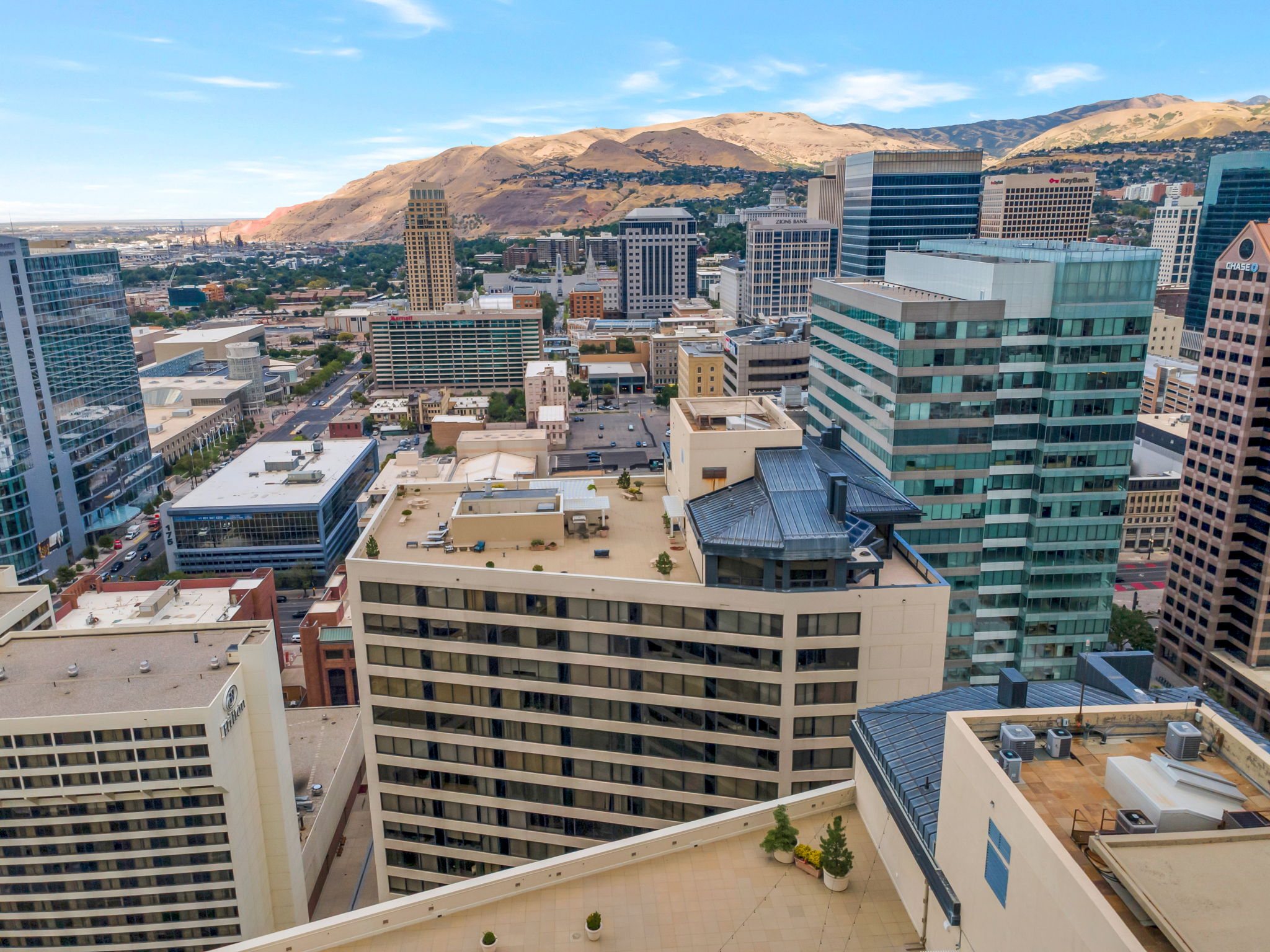 Urban cityscape featuring multiple high-rise buildings and distant mountain ranges