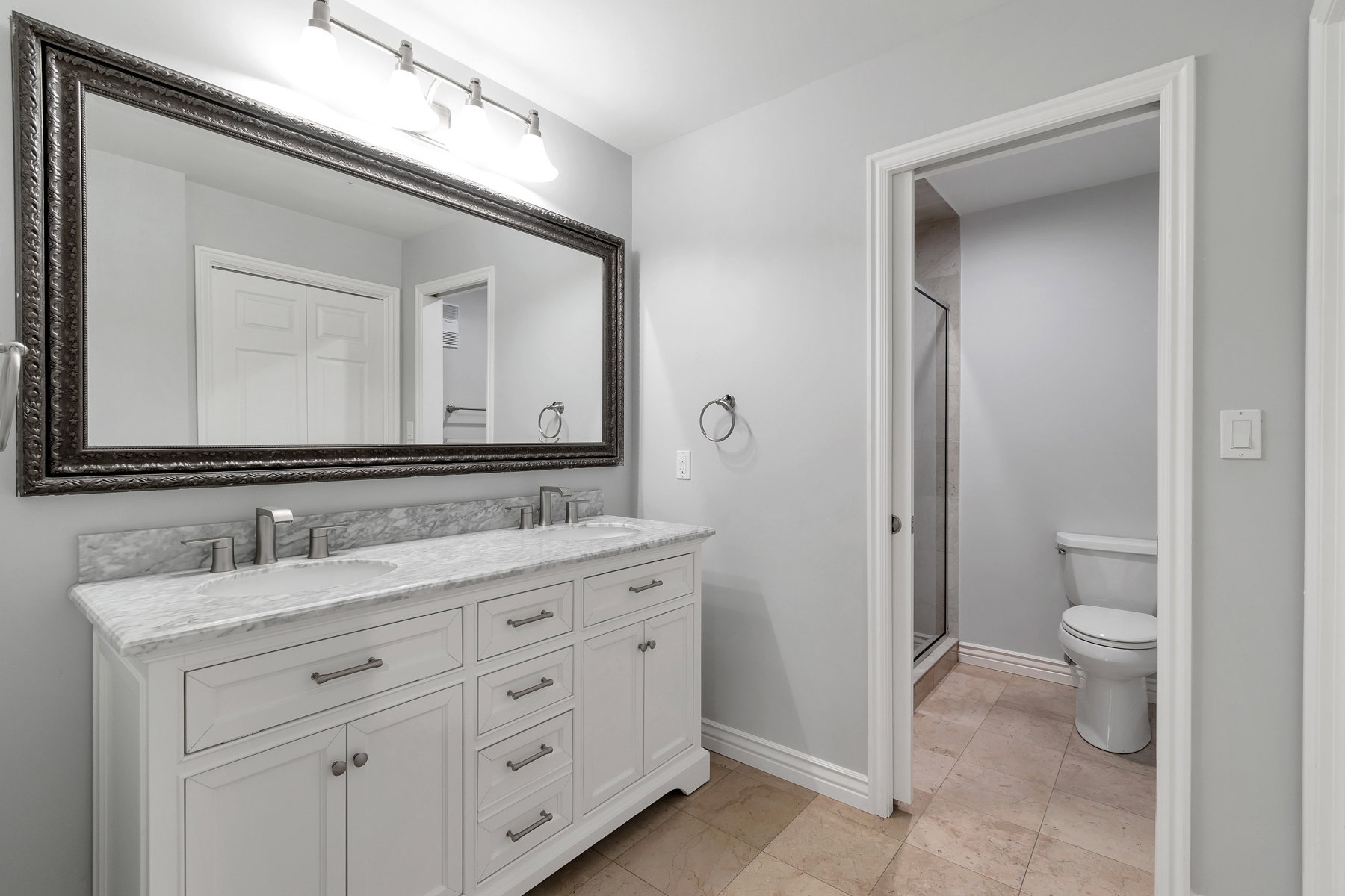 Primary bathroom featuring double vanity white cabinetry, granite countertops
