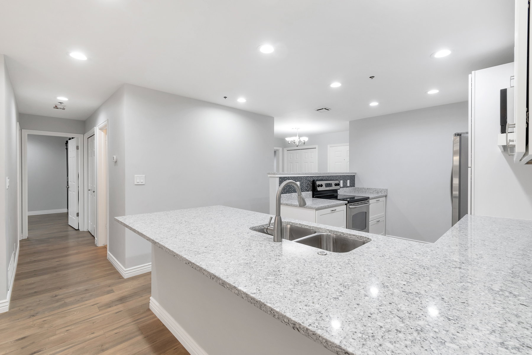 Kitchen featuring granite countertops, a double basin sink with a gooseneck faucet, and white cabinetry