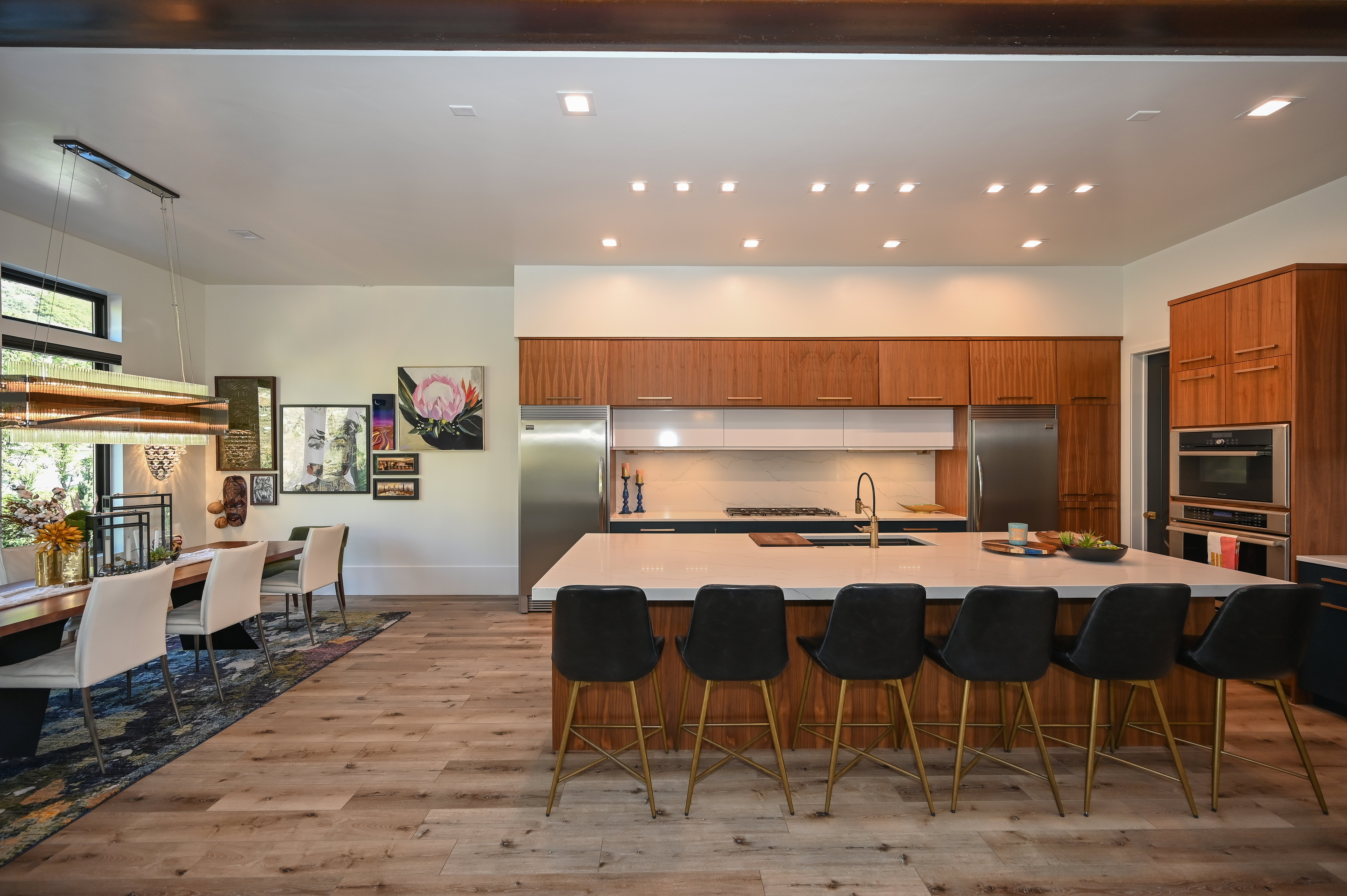Gourmet kitchen featuring a large island with white stone countertop, built-in stainless steel appliances, wood-finish cabinetry, and wood-finish flooring