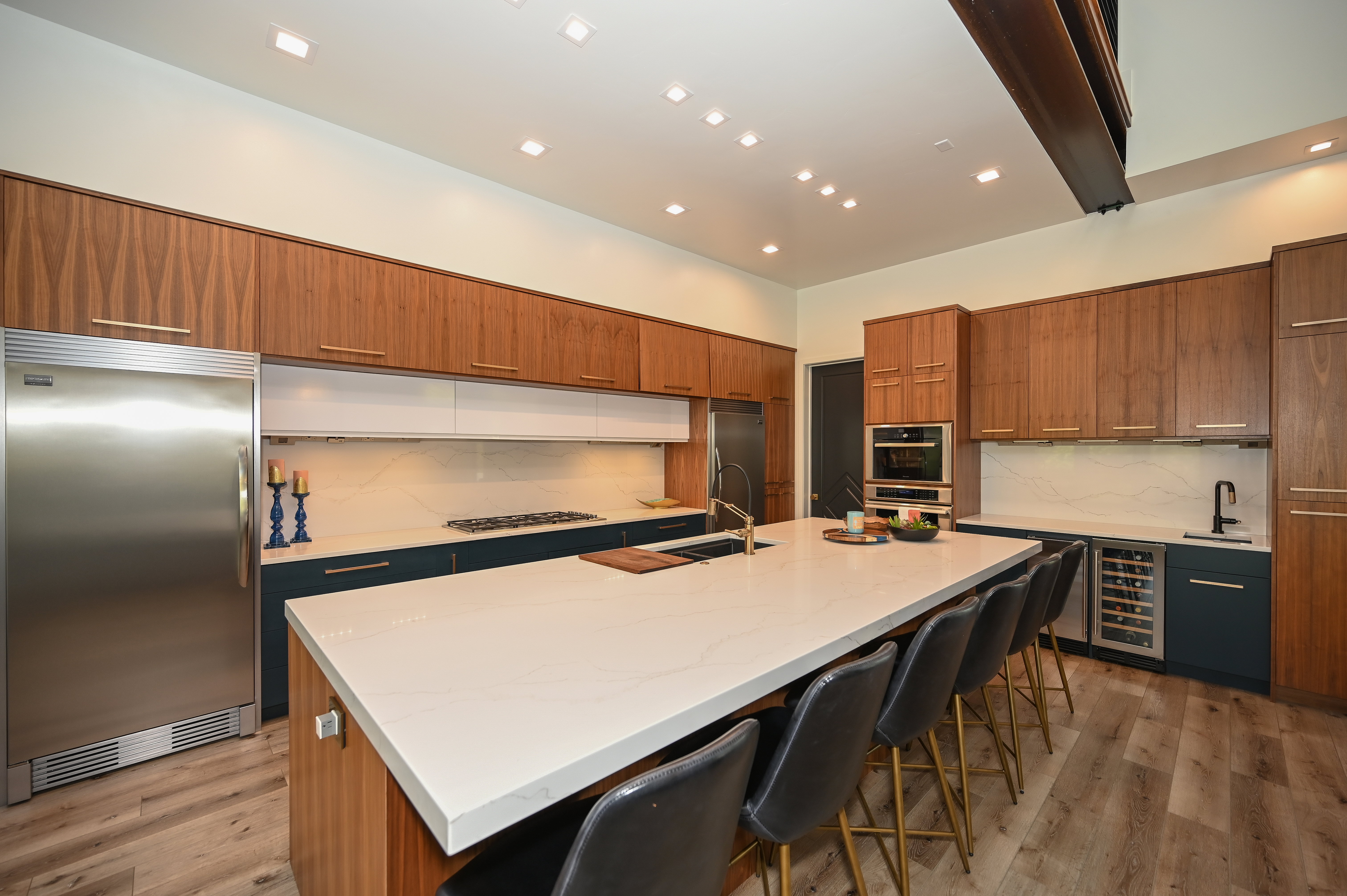 Modern kitchen featuring a large central island with seating, wood-finish flooring, and recessed lighting