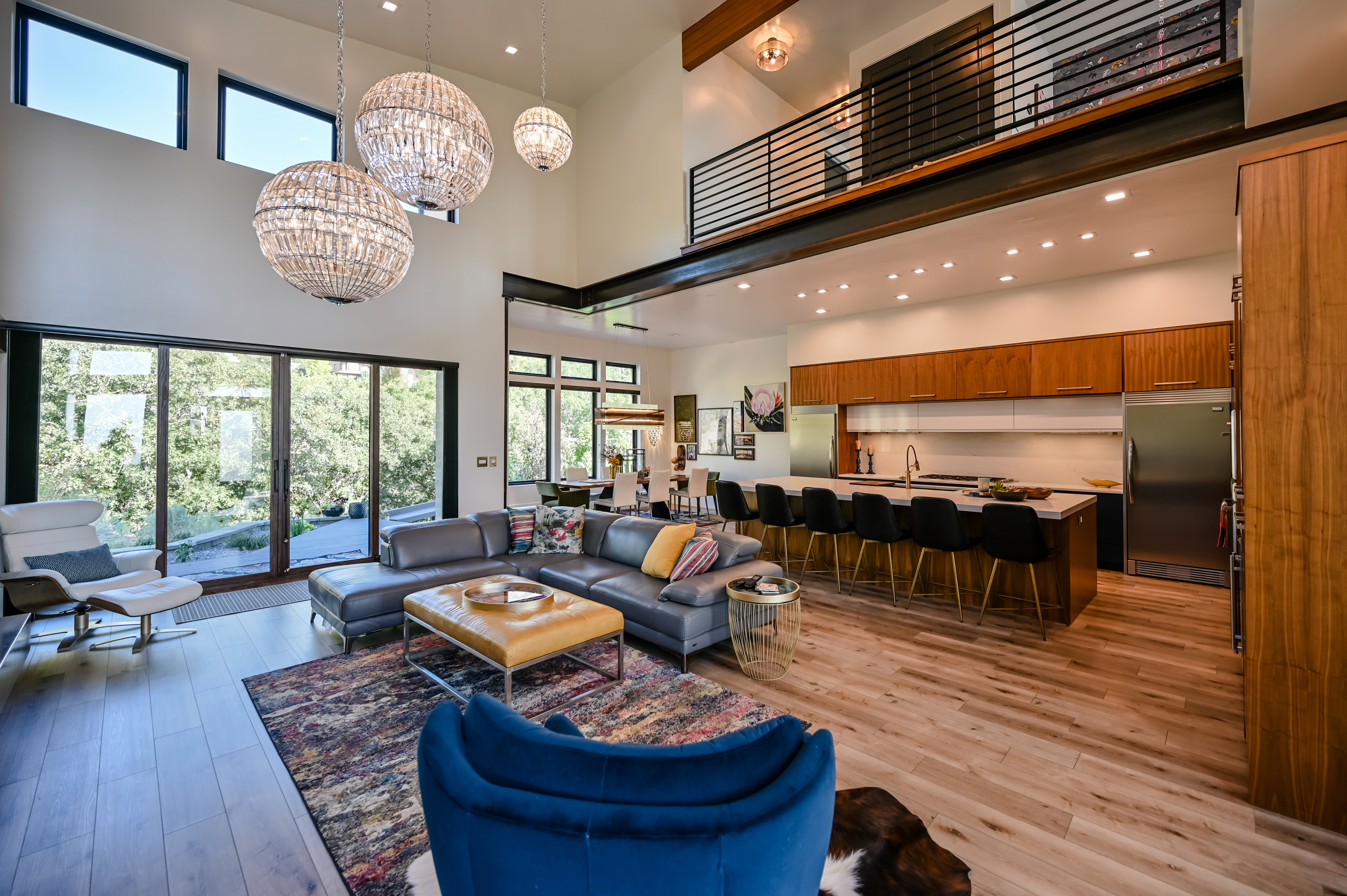 Expansive open-concept living space featuring high ceilings, wood-finish flooring, and large sliding glass doors