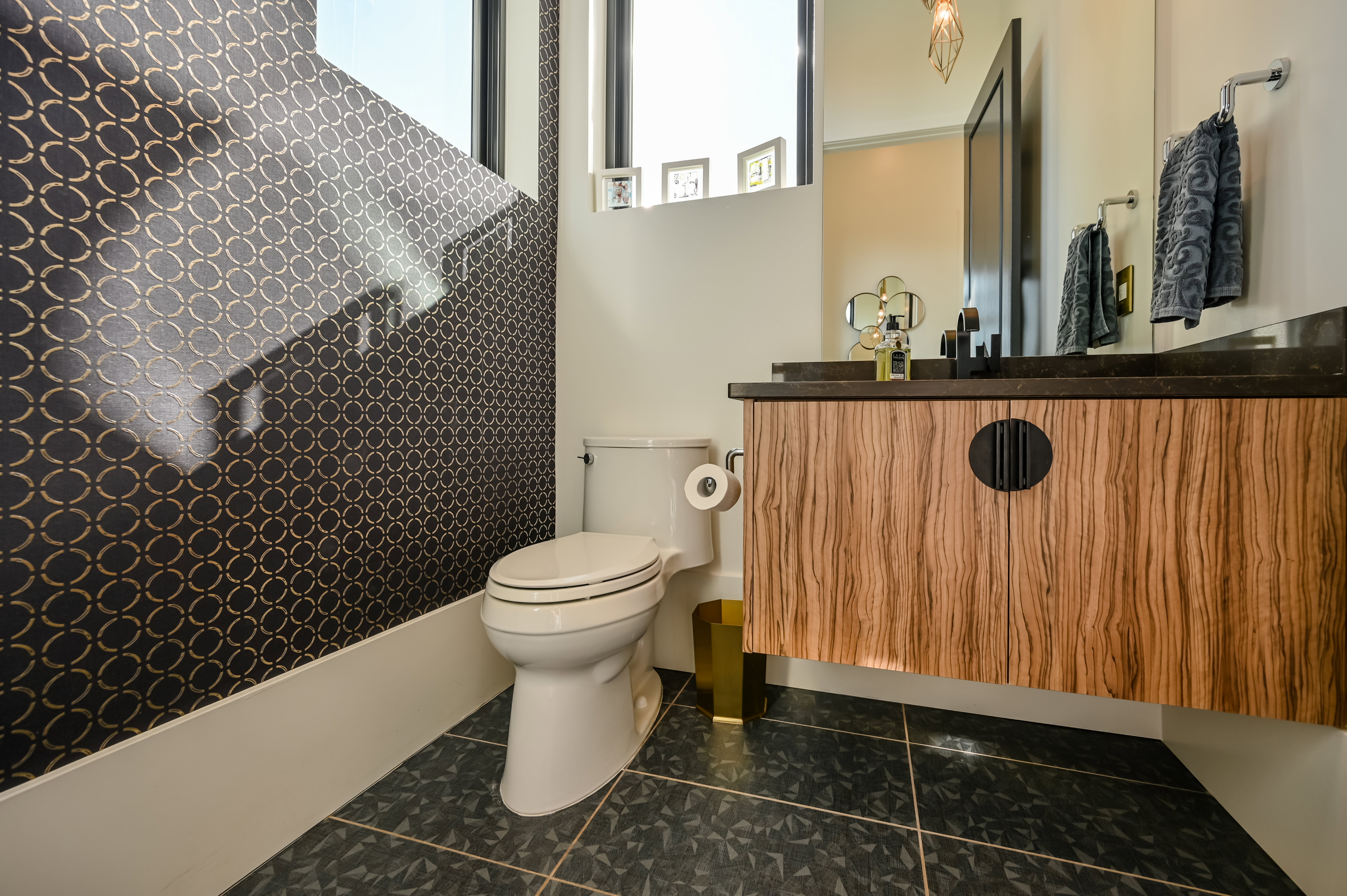 Floating wood-finish vanity with a dark countertop and a wall-mounted faucet