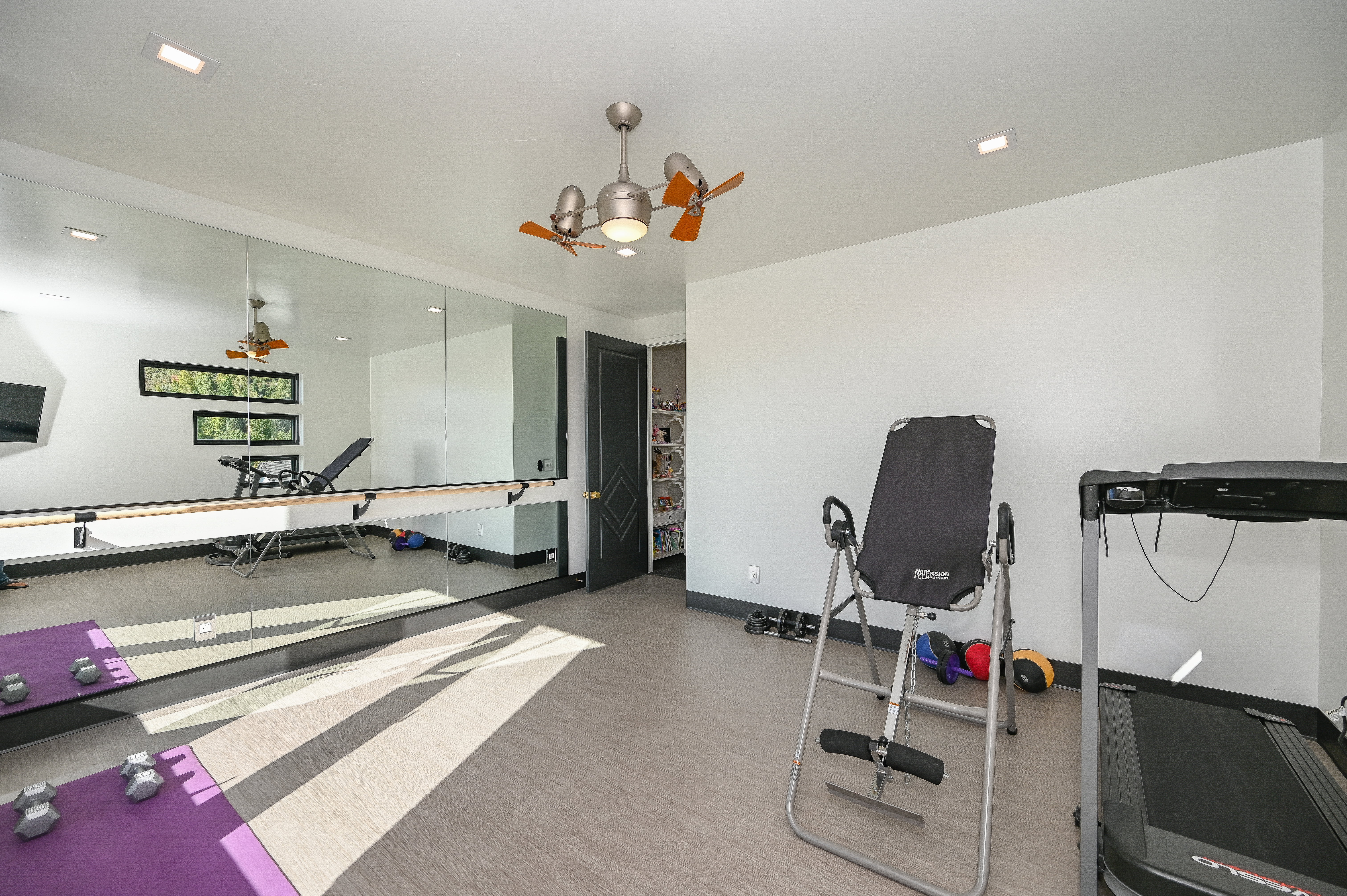 Dedicated fitness room featuring a full wall of mirrors with a ballet barre, recessed lighting, and a ceiling fan