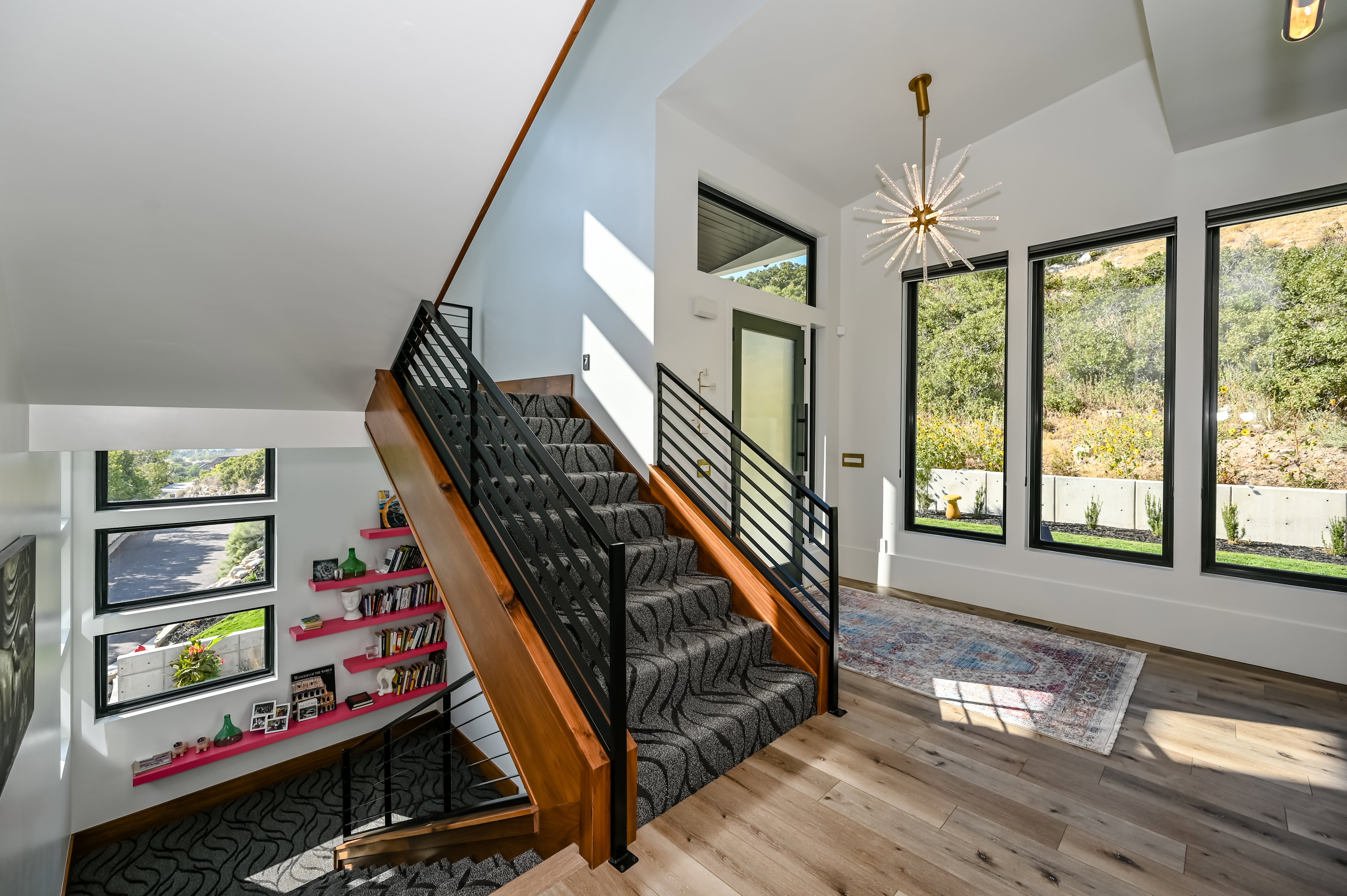 Foyer featuring a modern staircase with wood-finish treads and metal railings, large floor-to-ceiling windows, and wood-finish flooring