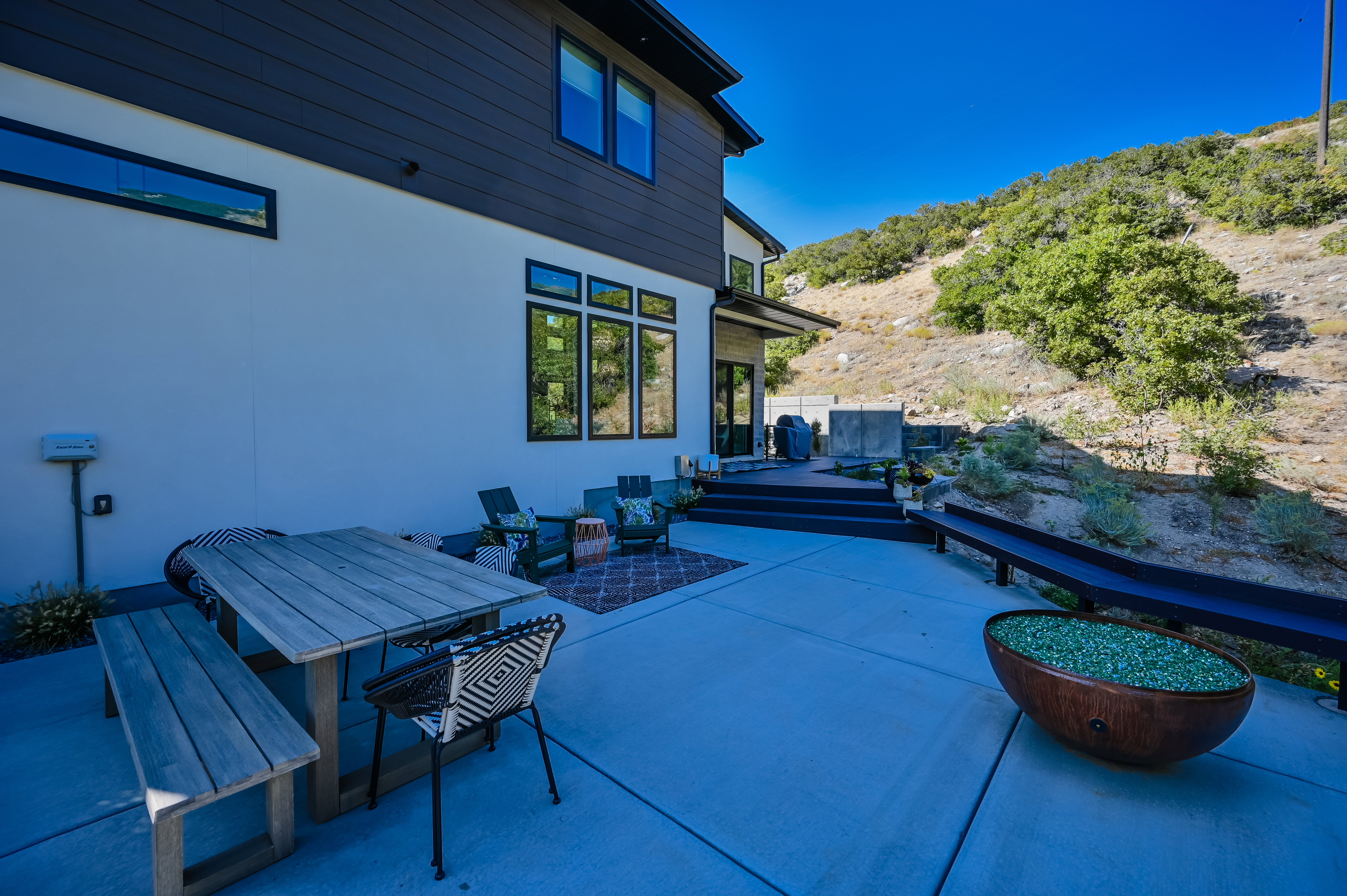 Expansive concrete patio with a tiered deck, large windows, and modern exterior siding