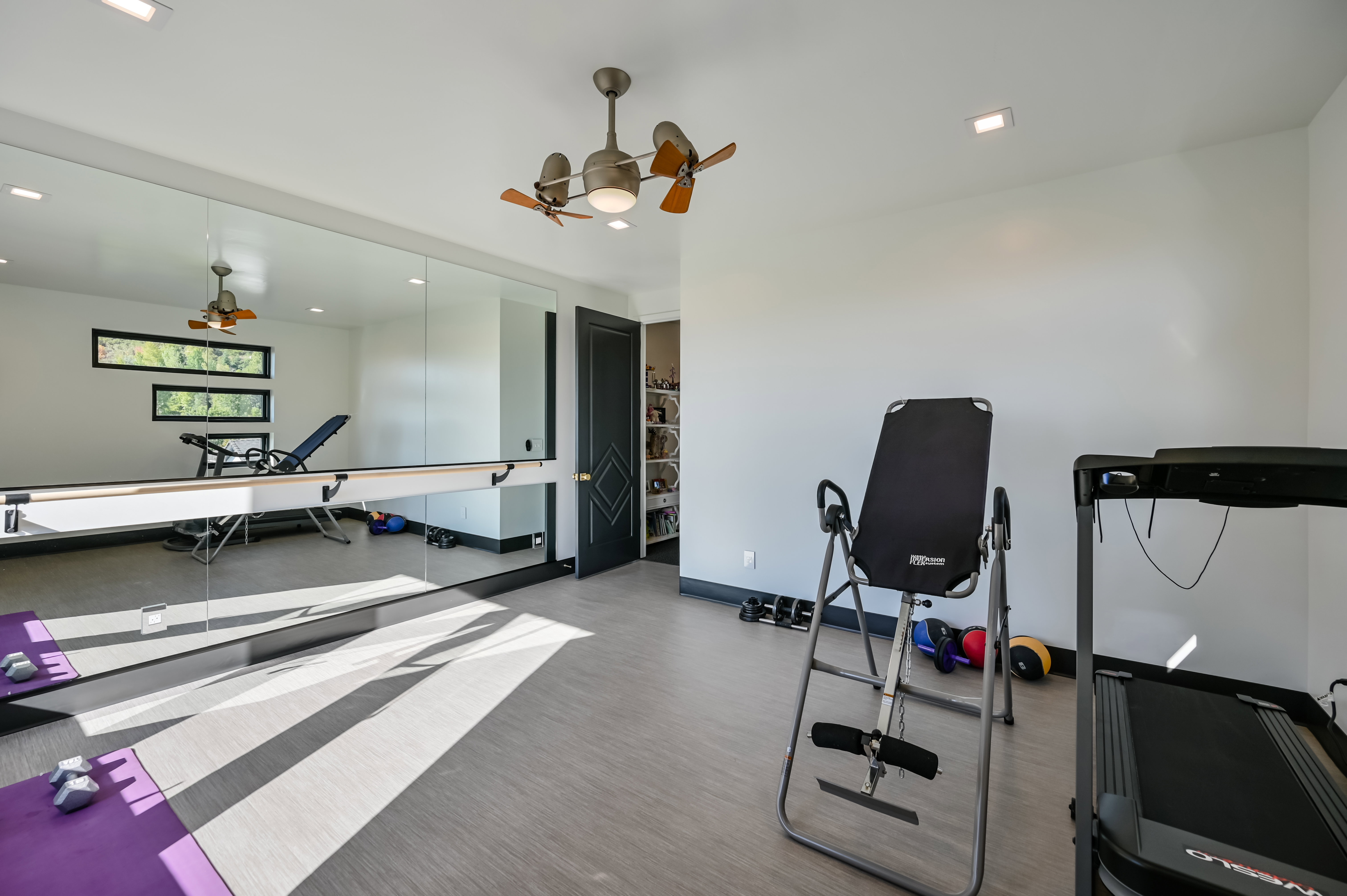 Dedicated fitness space featuring extensive mirrored walls, a built-in ballet barre, recessed lighting, and a ceiling fan